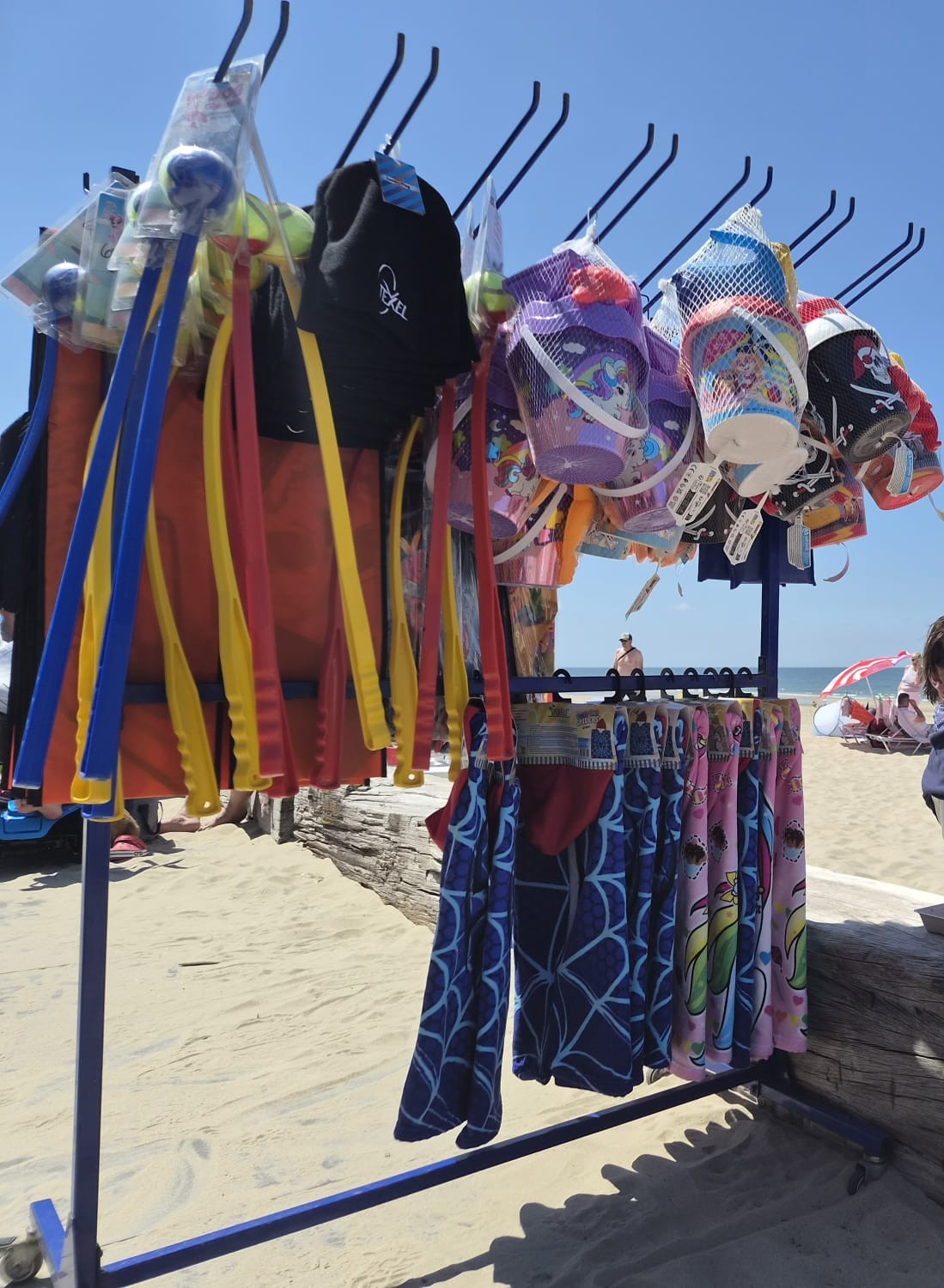 Rek met kinderspeelgoed, emmertjes en vliegers op het zand