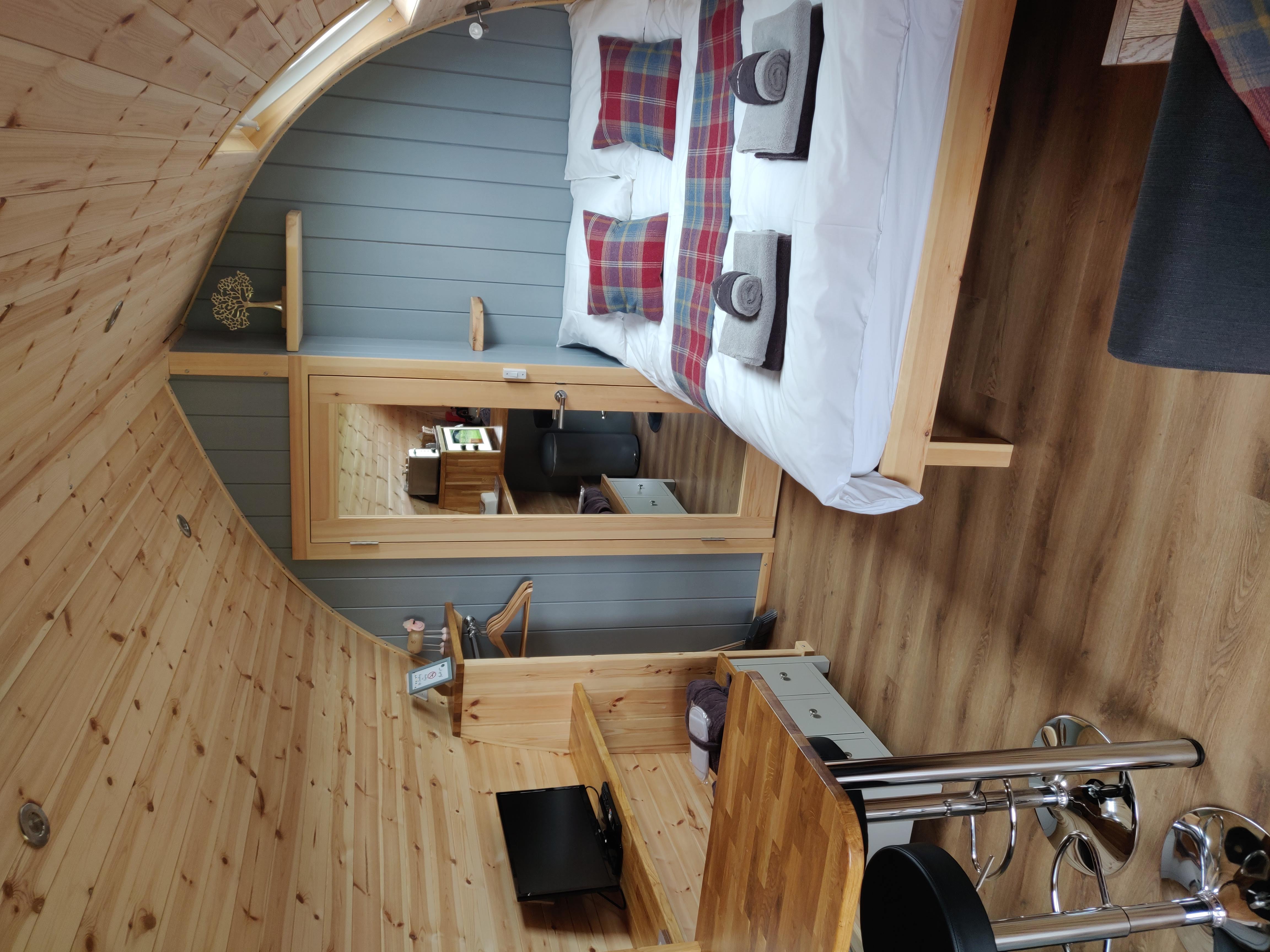 Interior of the Holly luxury glamping pod showing a comfortable double bed, dining area, and well-equipped kitchenette
