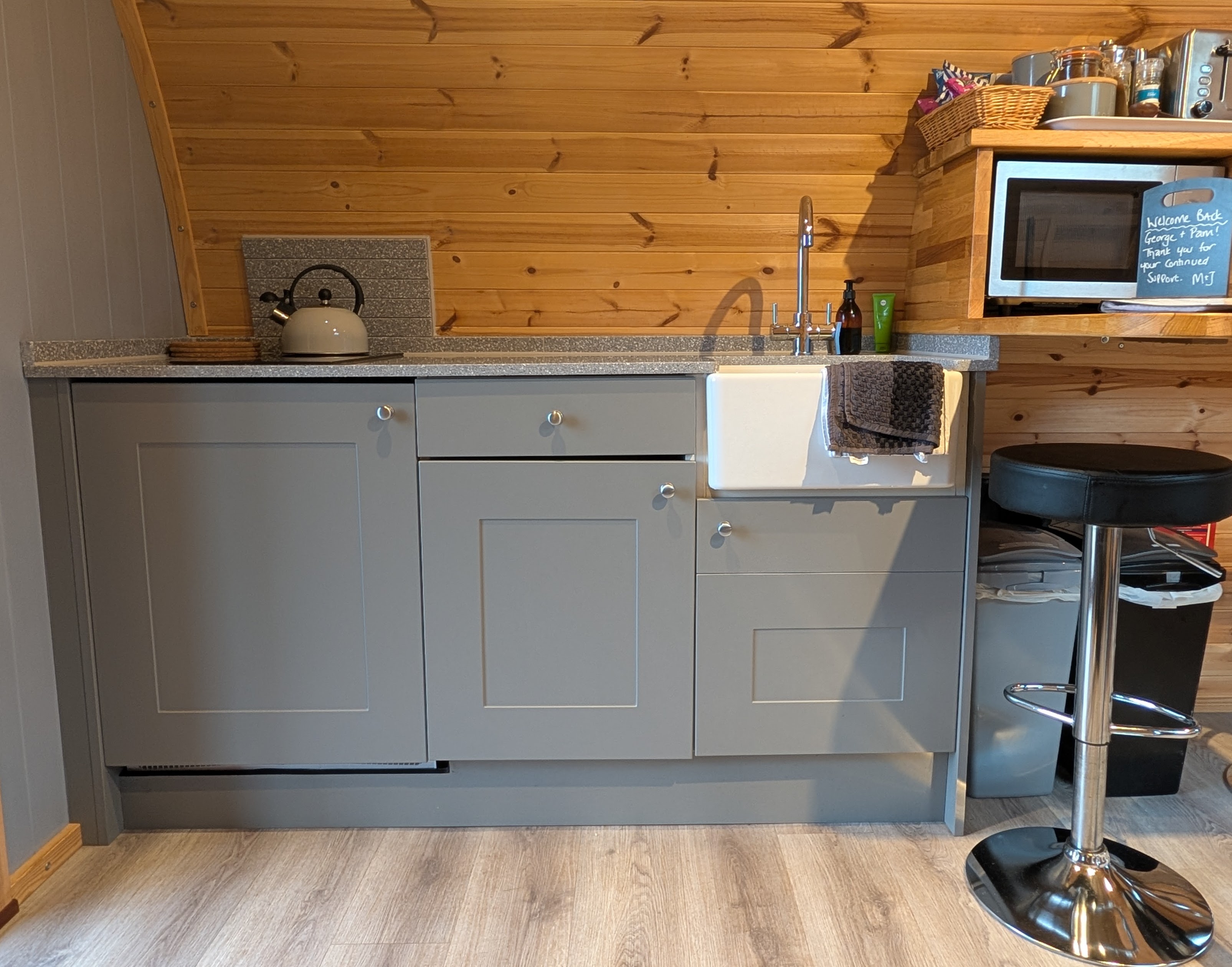 Fully equipped kitchen in the luxury glamping pod with sink, kettle, microwave, and grey shaker cabinets