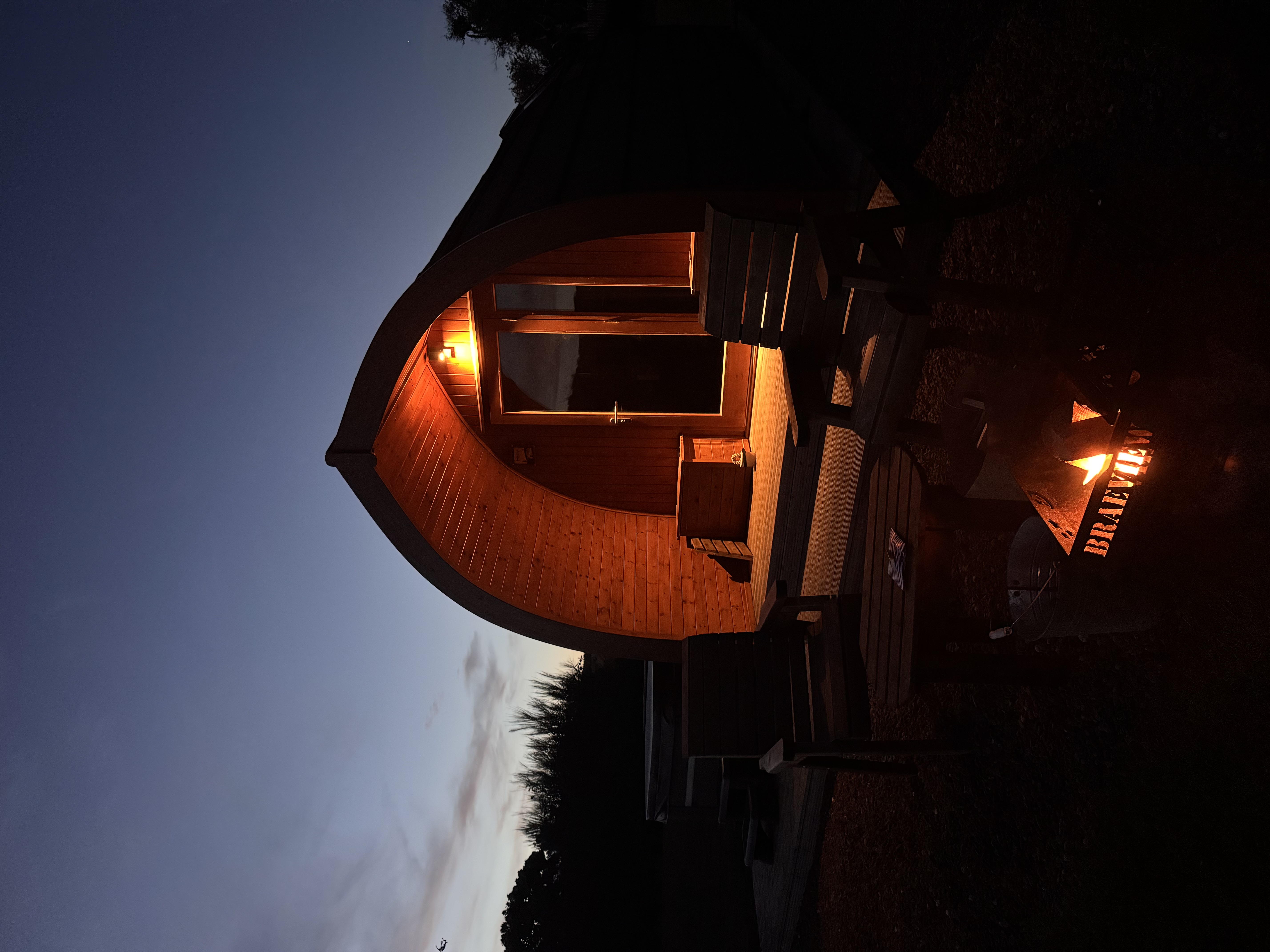 Juniper Hot Tub Pod exterior at evening with warm inviting light at Braeview Escapes