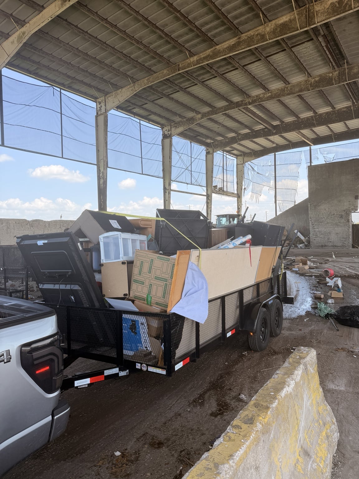 Lift & Load Hauling truck and utility trailer loaded with furniture and household items at a disposal facility.