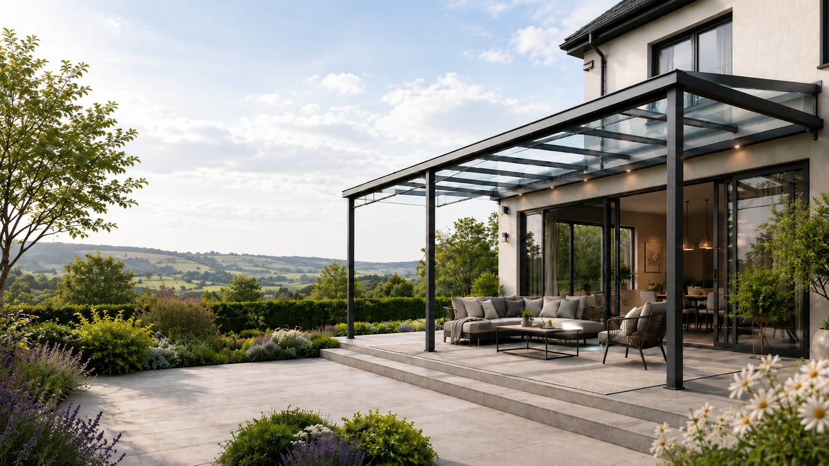 A wall-mounted aluminium glass veranda with anthracite grey frame overlooking a landscaped garden and rolling English countryside