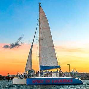 A bride and groom kissing on the bow of a catamaran at sunset
