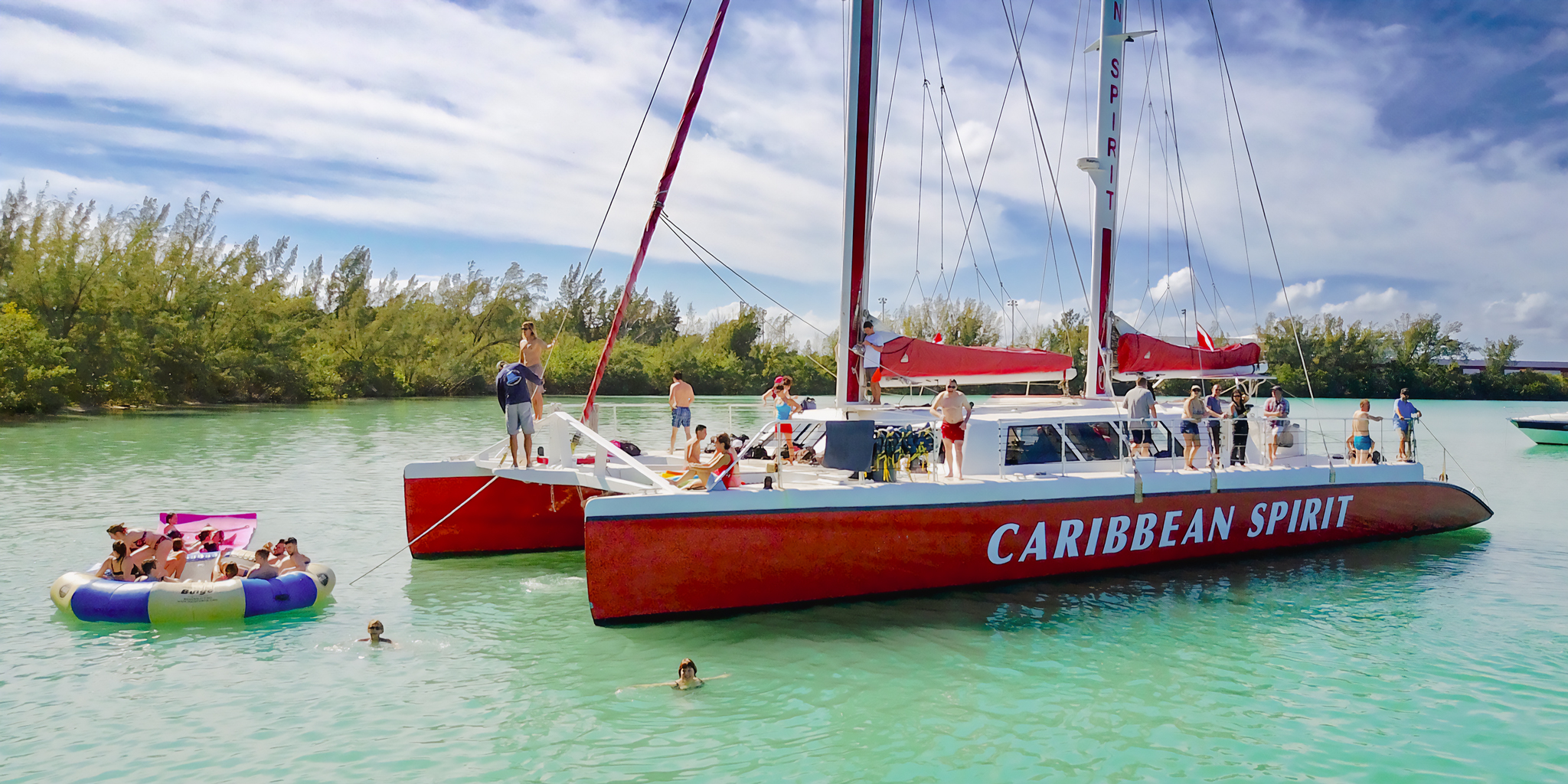 A large corporate group enjoying a catered event on the deck of the Caribbean Spirit catamaran with the Miami skyline behind them