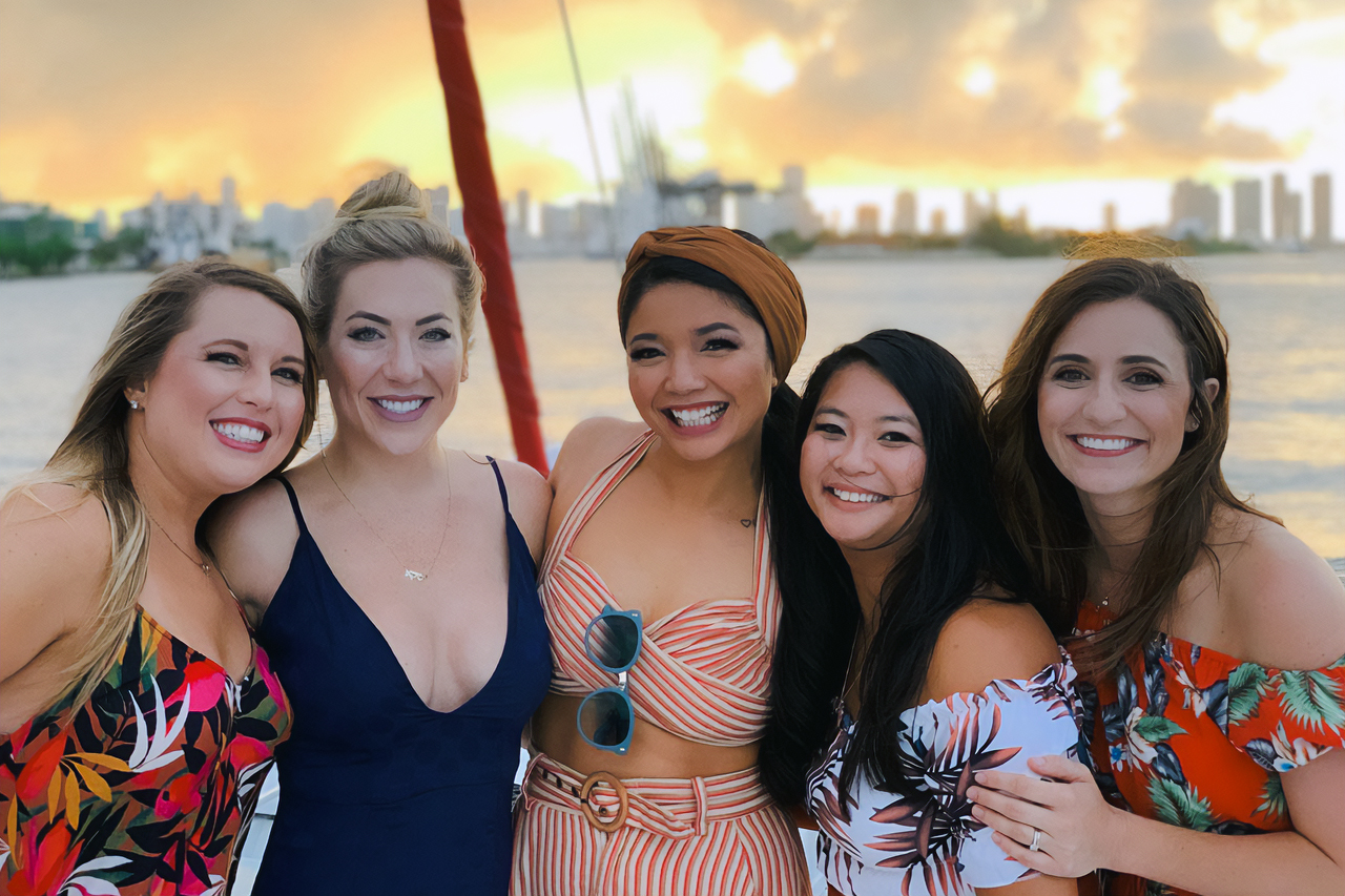 Group of friends posing on the boat at sunset