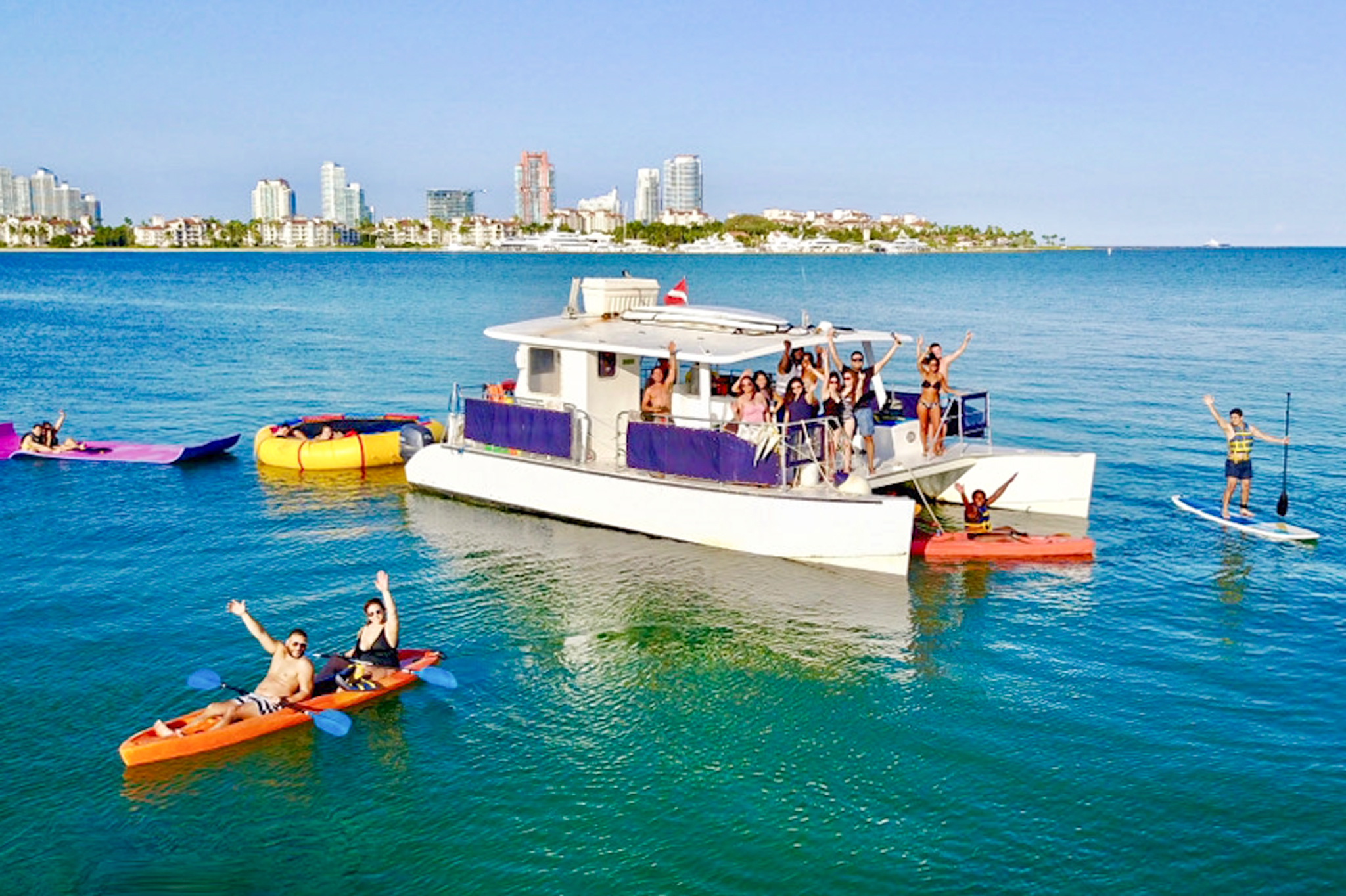 Tranquility anchored near a tropical island with guests swimming