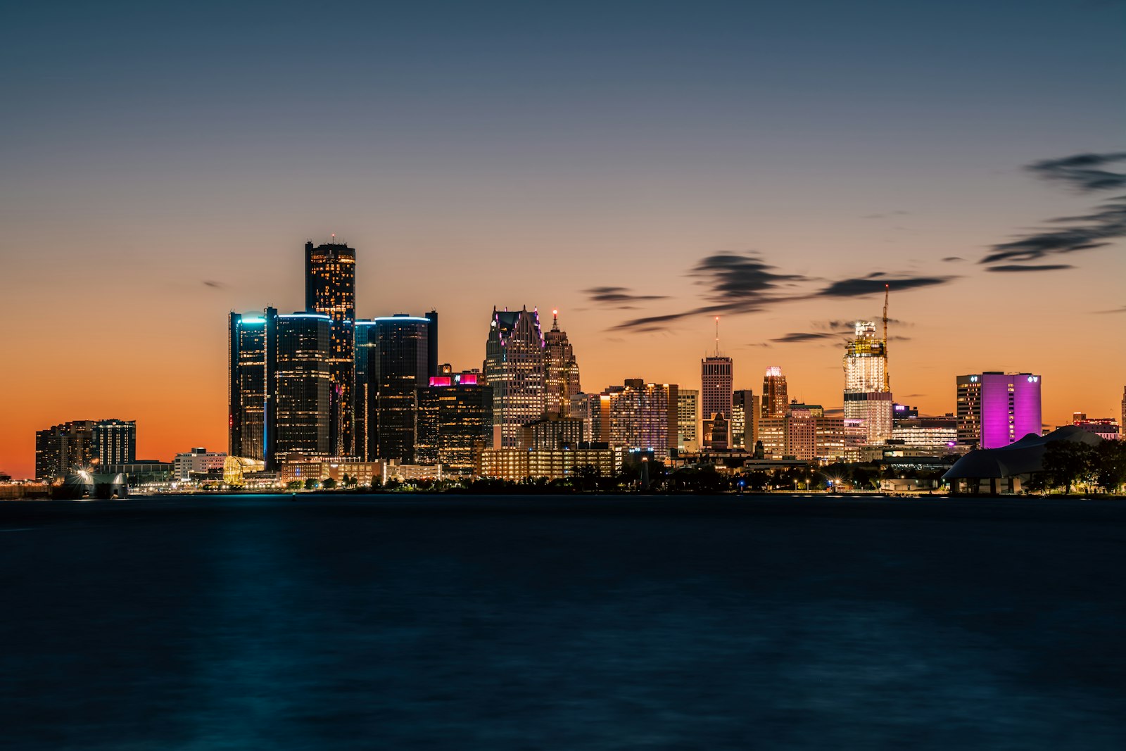 Detroit skyline at night with illuminated skyscrapers reflecting on the Detroit River