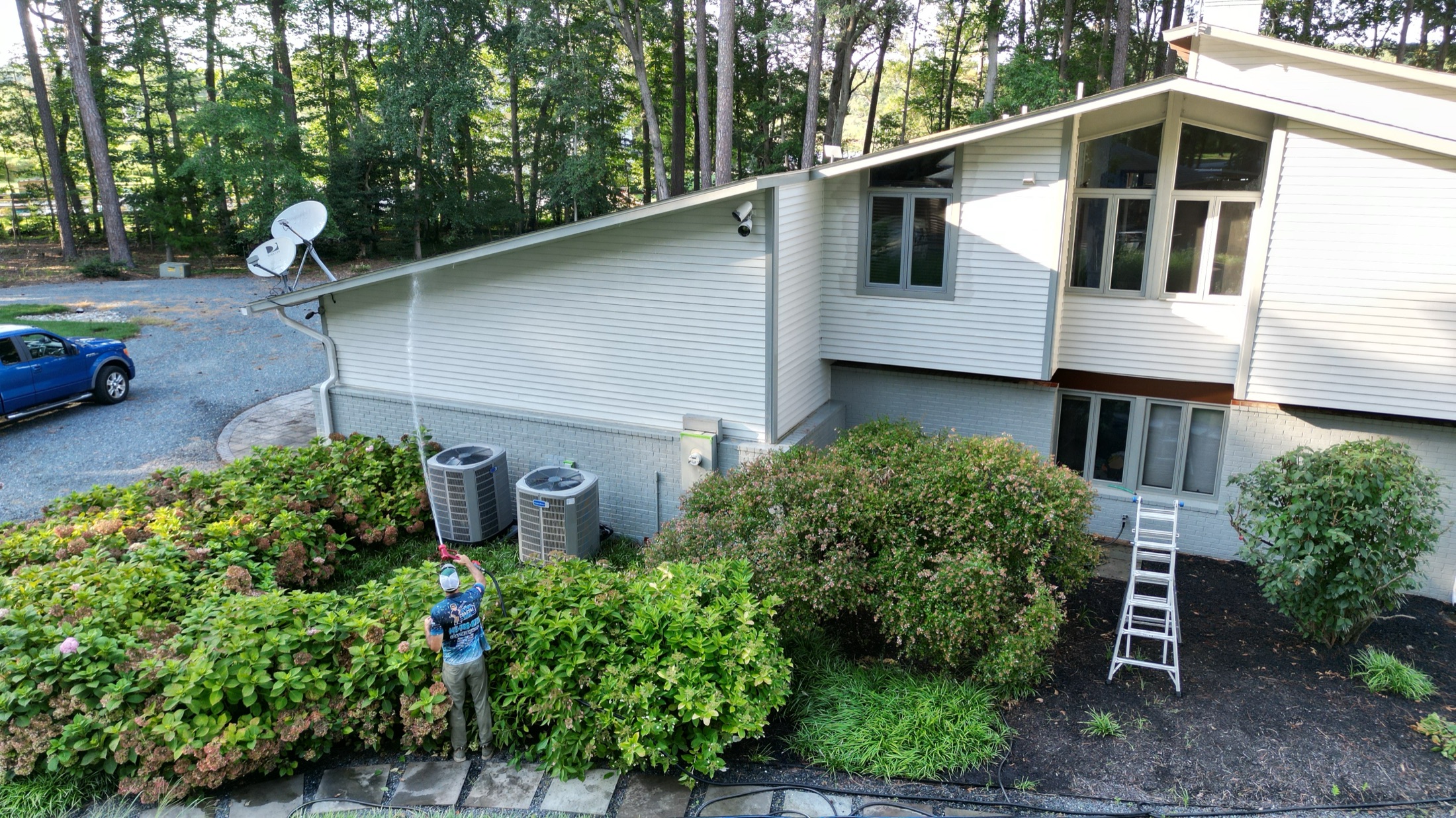 Aerial view of a Coastal Shine technician preparing to soft-wash the siding of a mid-century home surrounded by trees in Easton MD on Maryland's Eastern Shore