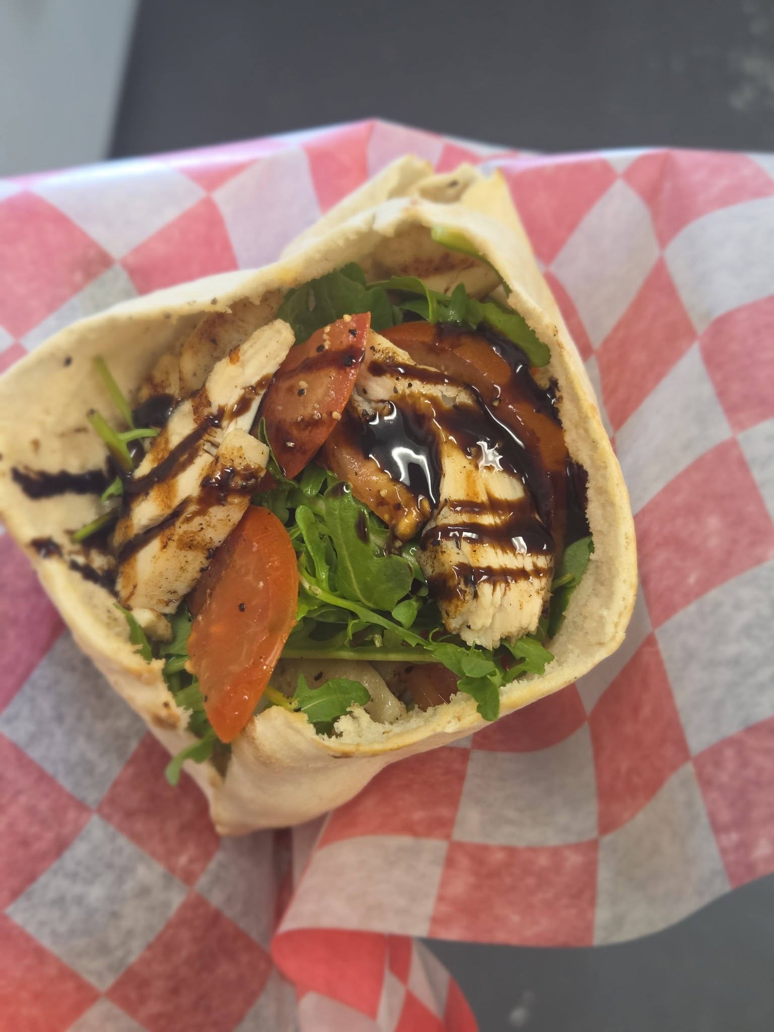 Chicken pita wrap with balsamic glaze on checkered paper