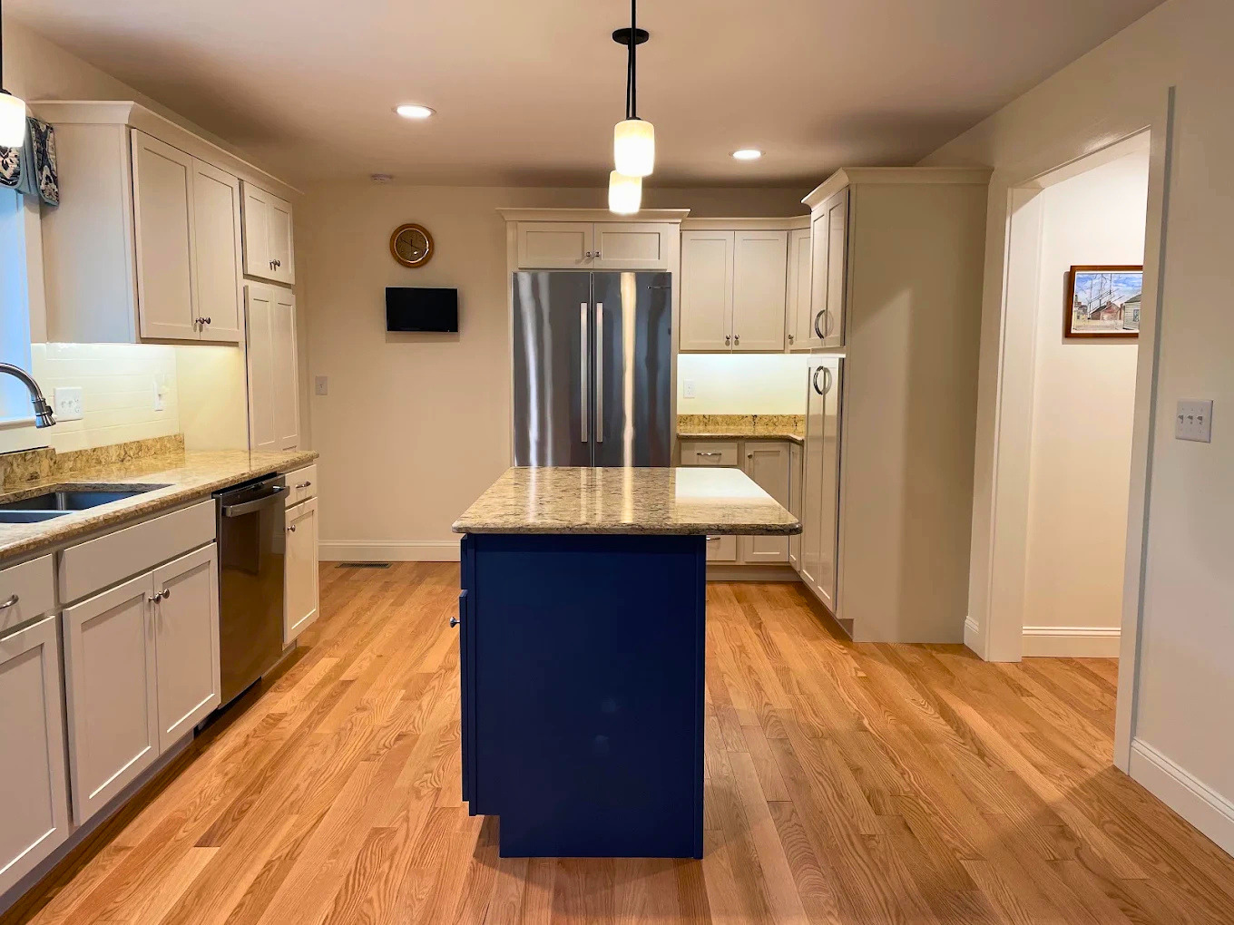 Cabinet refinishing with crisp white cabinetry and a navy accent island by Minute Men Painters