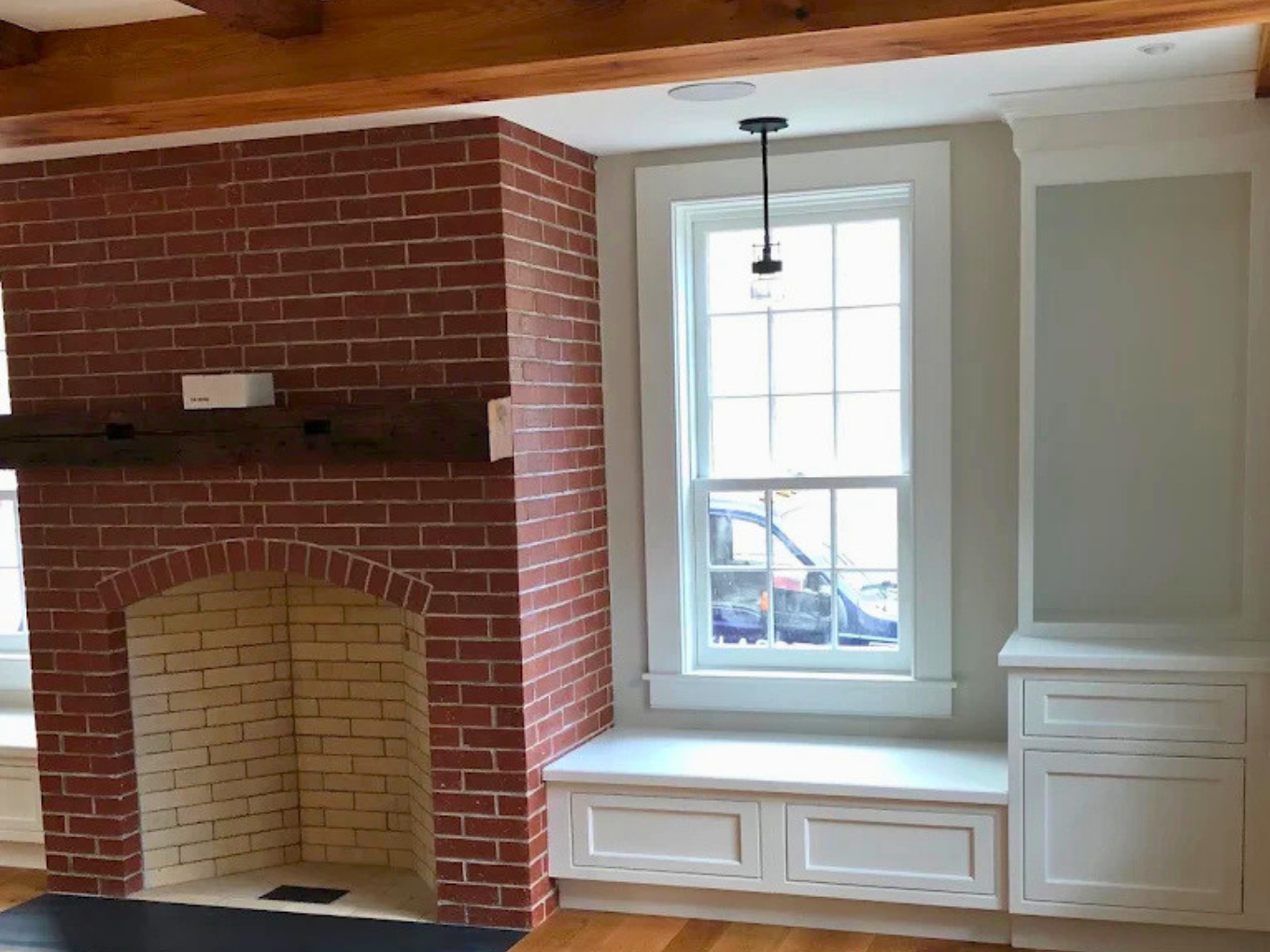 Interior painting around a brick fireplace with white built-ins and trim by Minute Men Painters