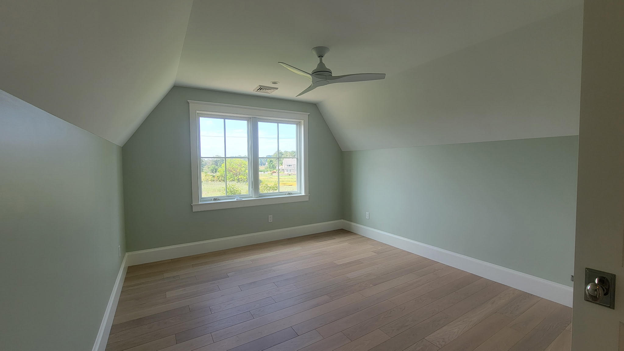 Completed residential interior bedroom painting with soft sage walls, vaulted ceiling, and crisp white trim by Minute Men Painters