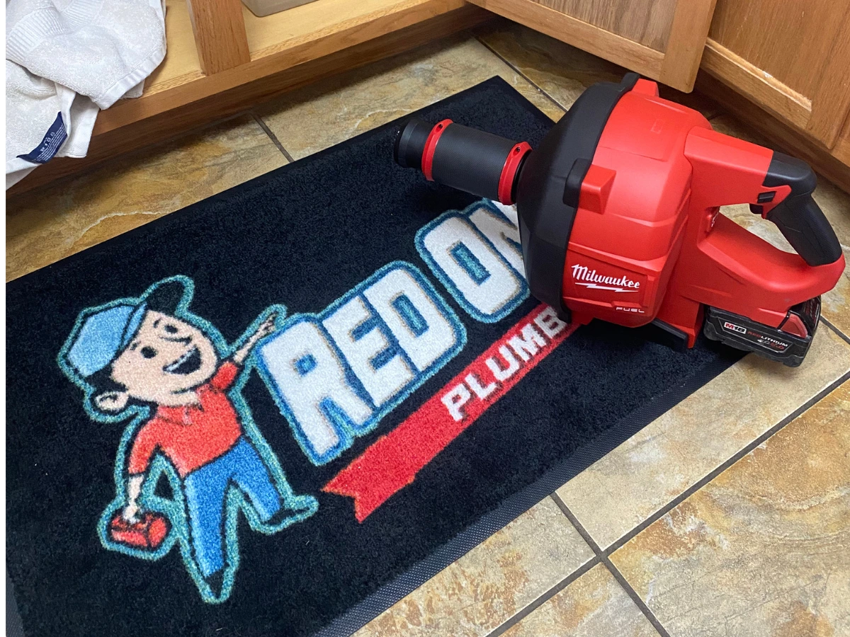Red One Plumbing drain cleaning equipment on a branded mat in Pearland TX
