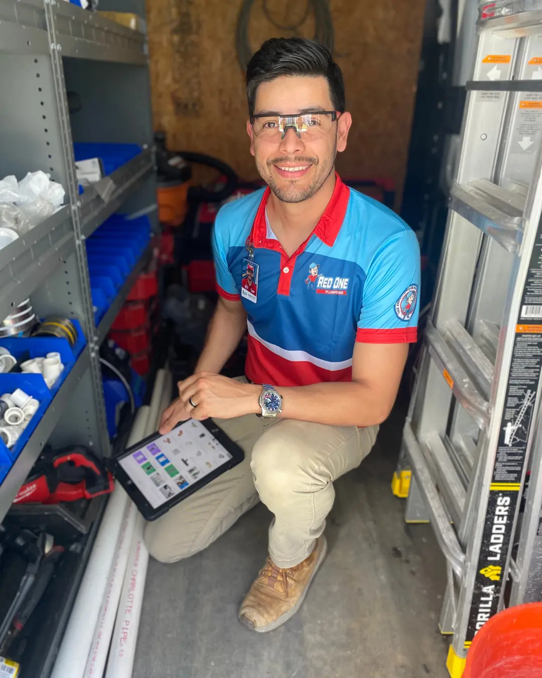 Professional Pearland plumber from Red One Plumbing reviewing service details on a tablet inside a fully stocked work van