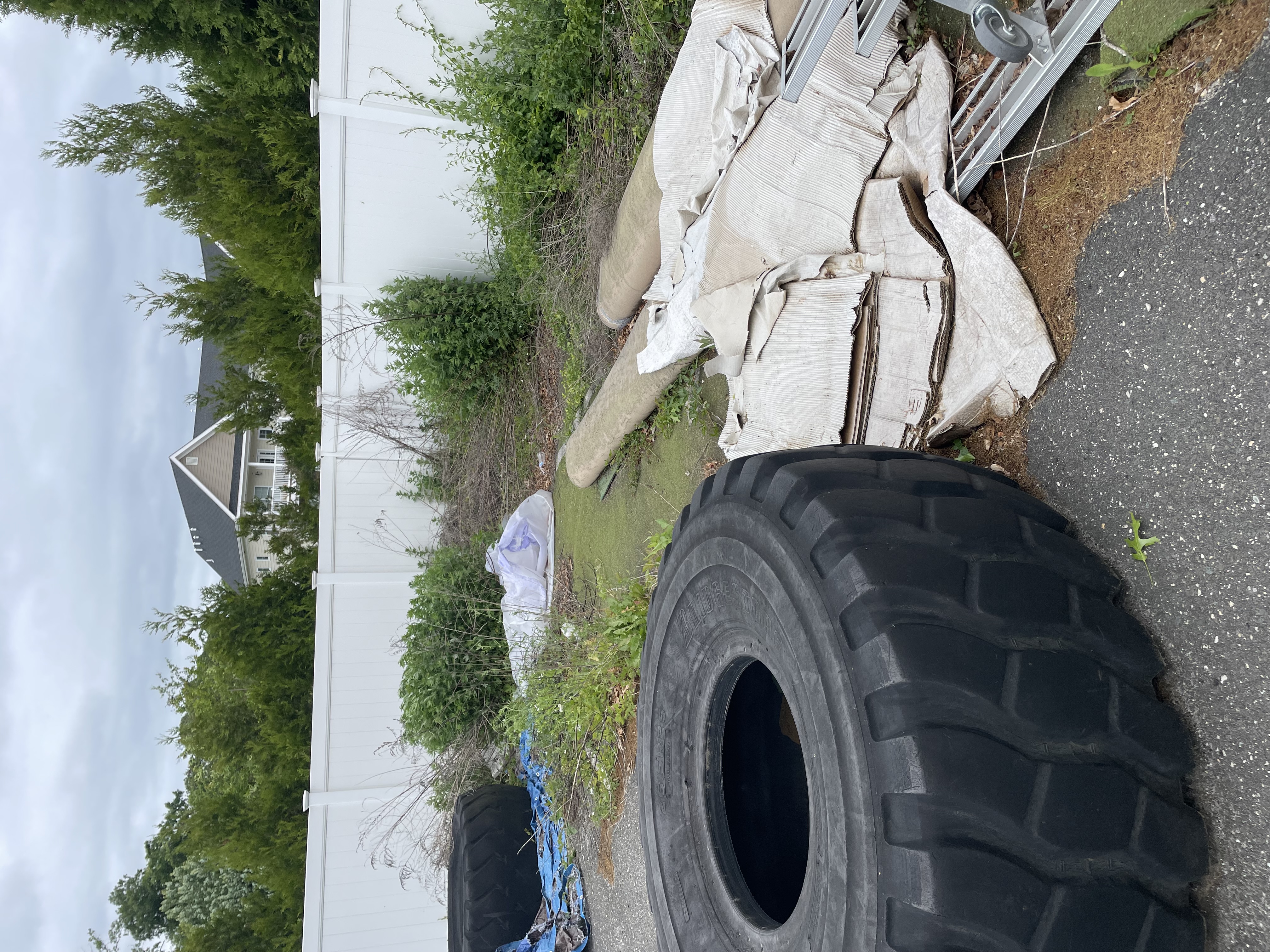 Large industrial tire and cardboard debris in a backyard