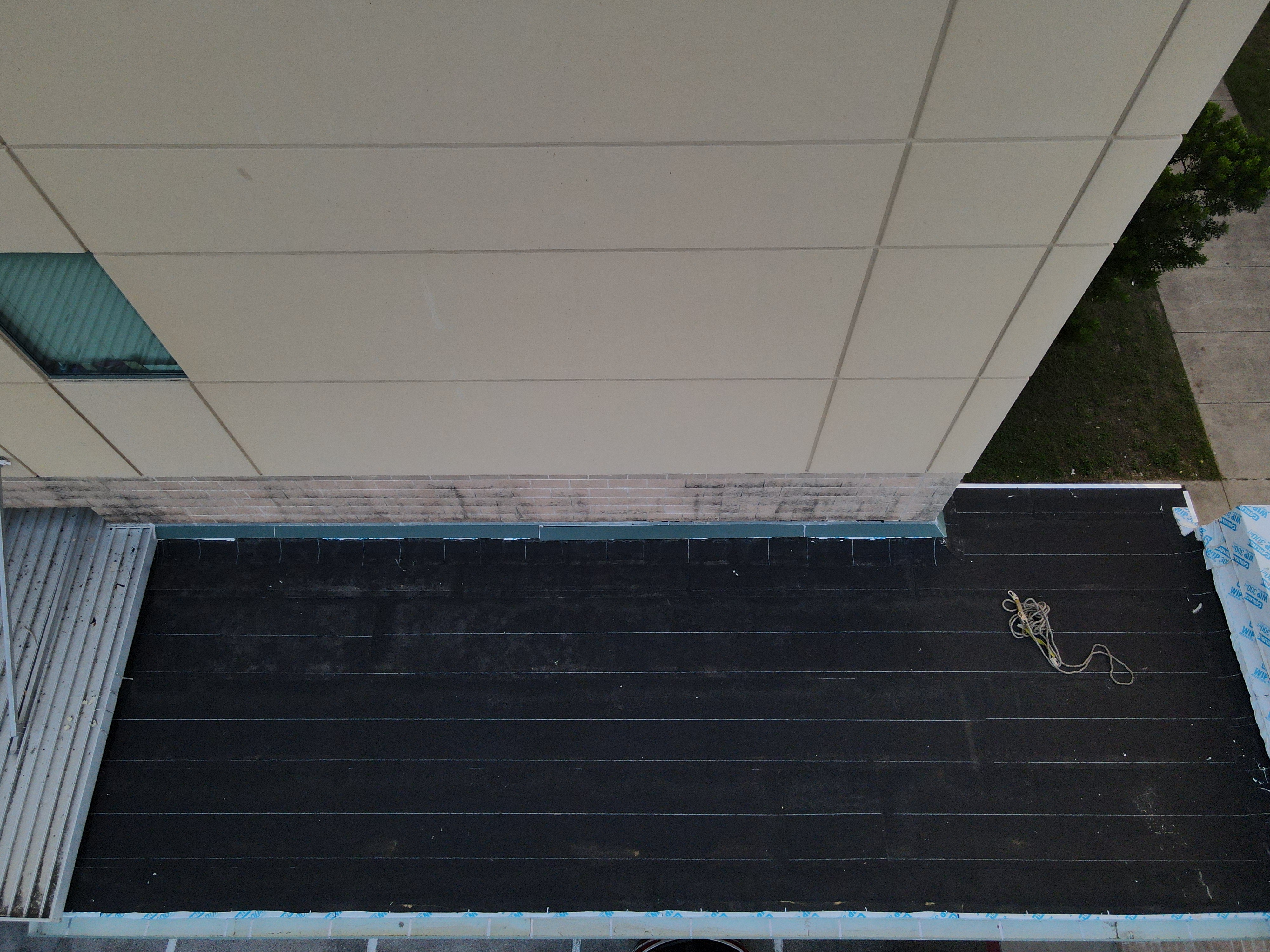 Roof inspection drone San Antonio commercial building facade panel curtain wall edge membrane installation close-up high-resolution aerial view Texas