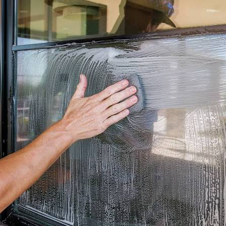Close up of a professional using 0000 grade ultra-fine steel wool on a soapy glass window pane for premium glass restoration in Boone, NC