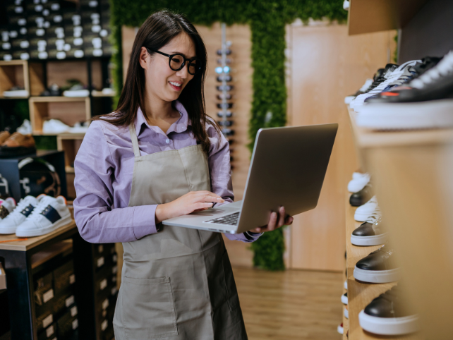 Retail store employee using laptop for inventory management