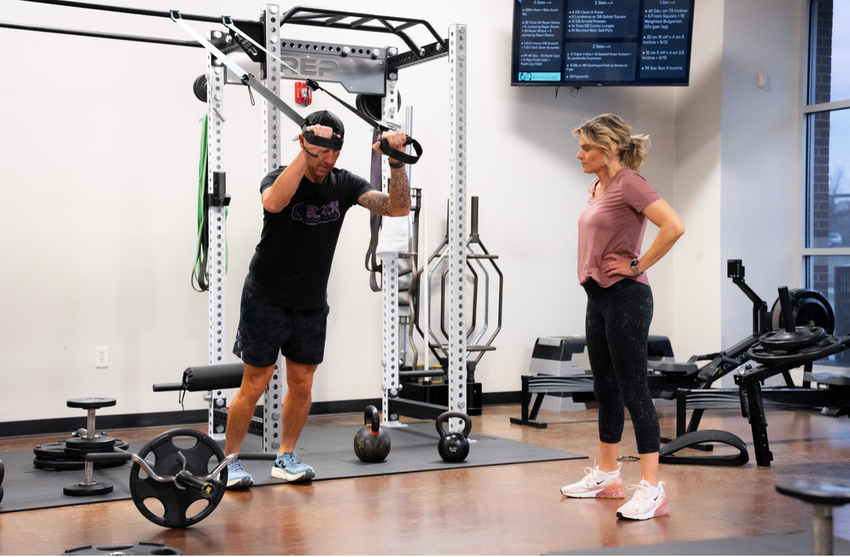Personal trainer coaching client in semi-private session at Black Clover Fitness Omaha