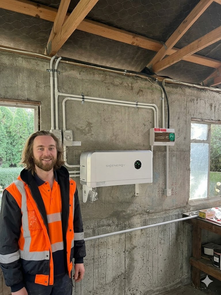 Geordie Munroe standing next to a newly installed solar inverter