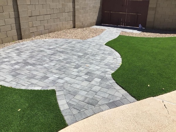 Gray paver patio with curved edges meeting turf
