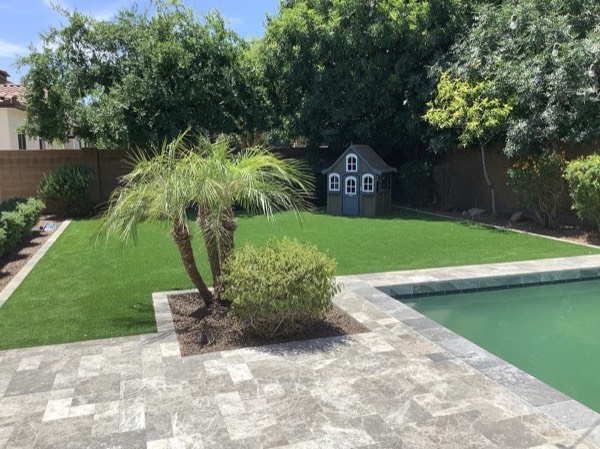 Lush backyard turf with pool deck and playhouse
