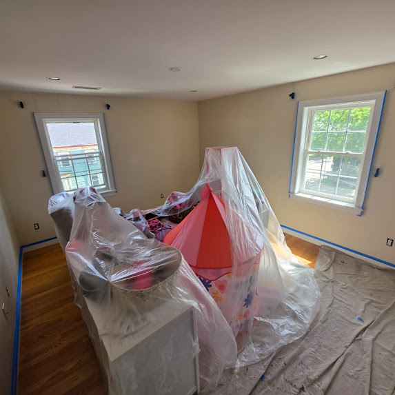 Beige room with tent covered in plastic for painting prep