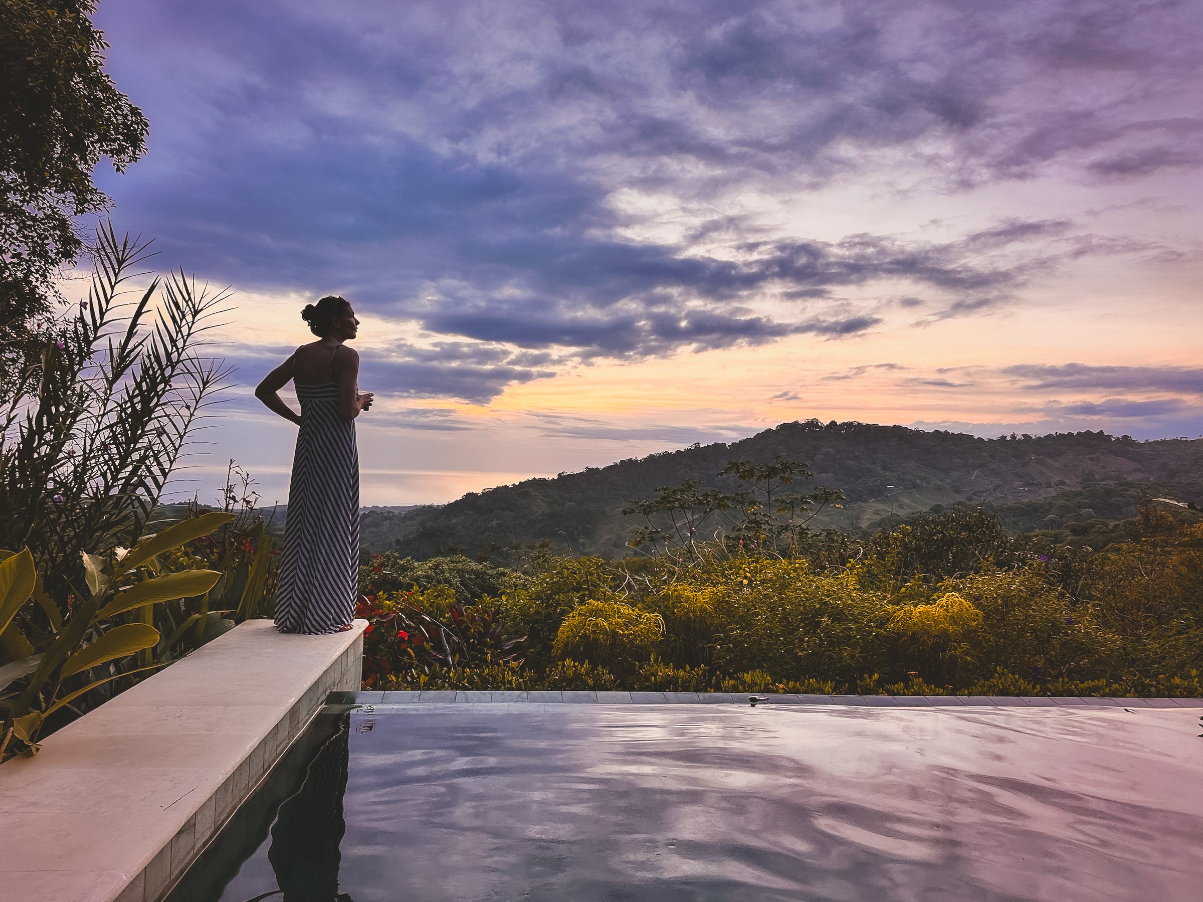 Woman silhouette at infinity pool during sunset