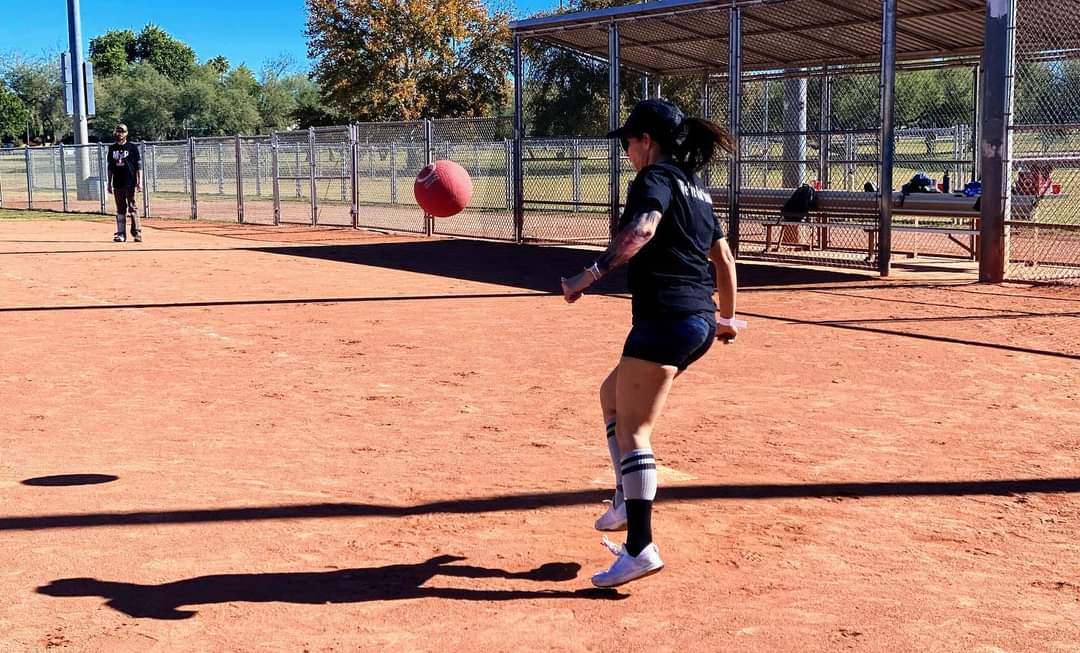 Female player making athletic contact with the red kickball at home plate
