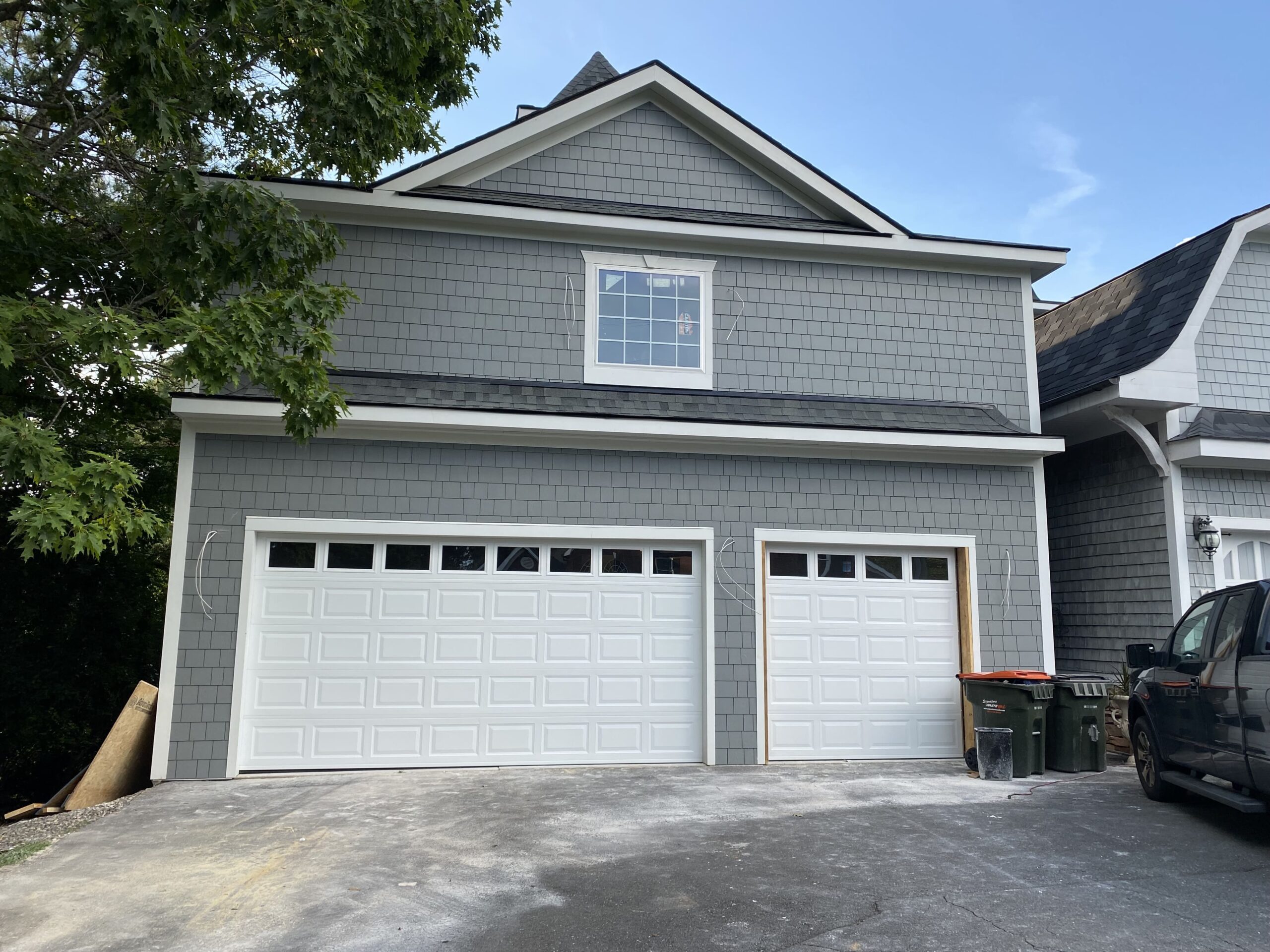 Garage Door Gators completed installation of dual white raised-panel garage doors with windows on a gray shingle home in Mint Hill NC