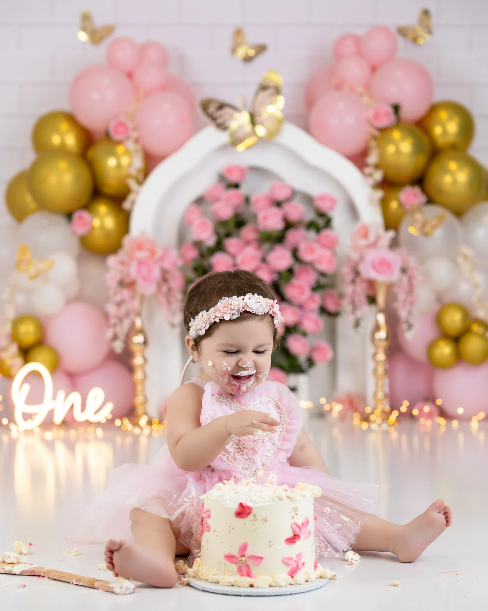 Pink and gold floral cake smash session with butterfly decorations