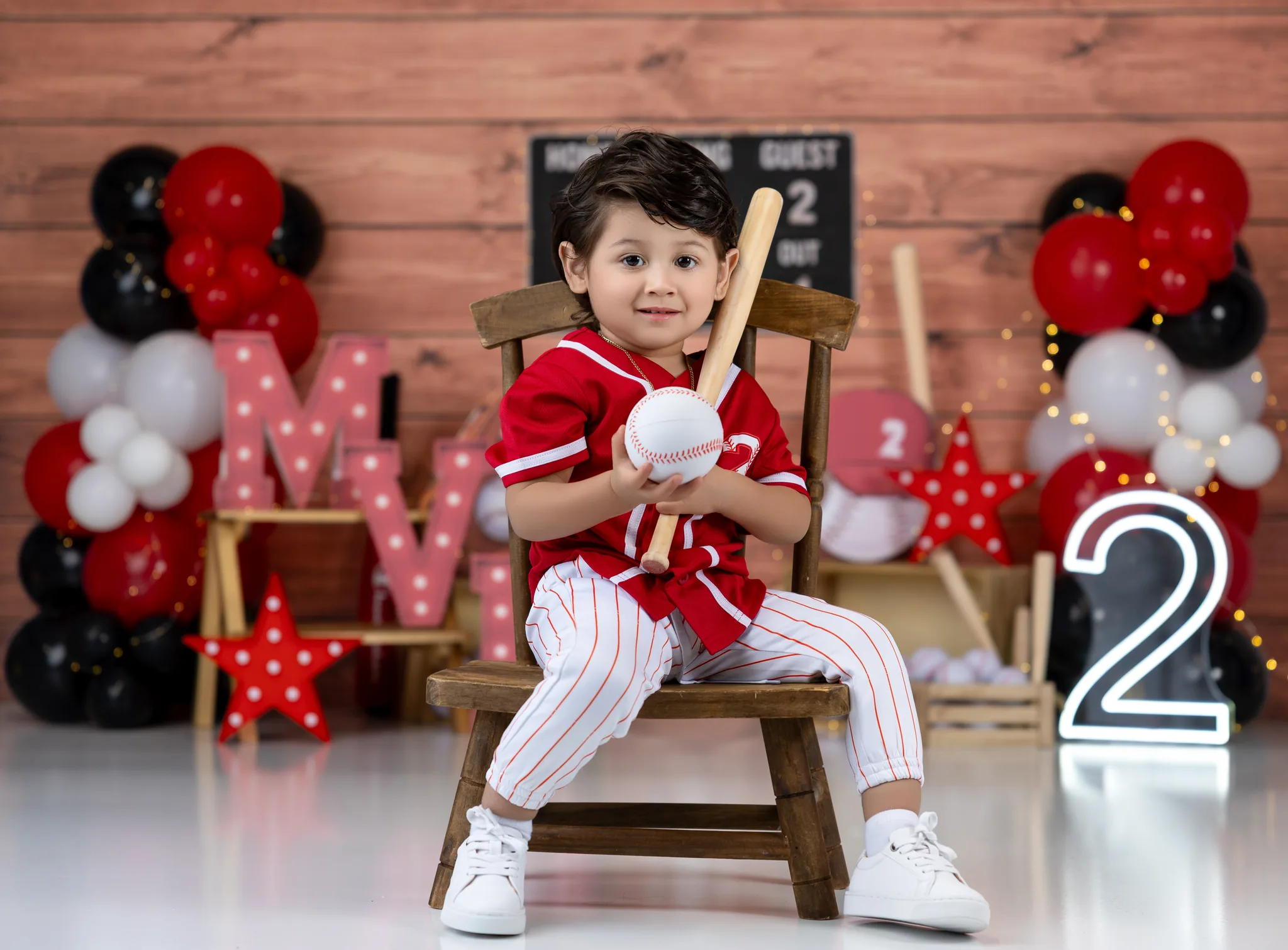 Baseball-themed 2nd birthday session with red pinstripe uniform and balloons