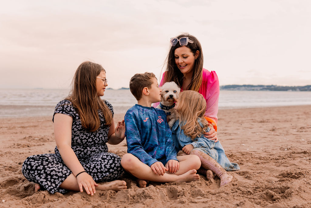 Beth relaxing on the beach with her children and their dog