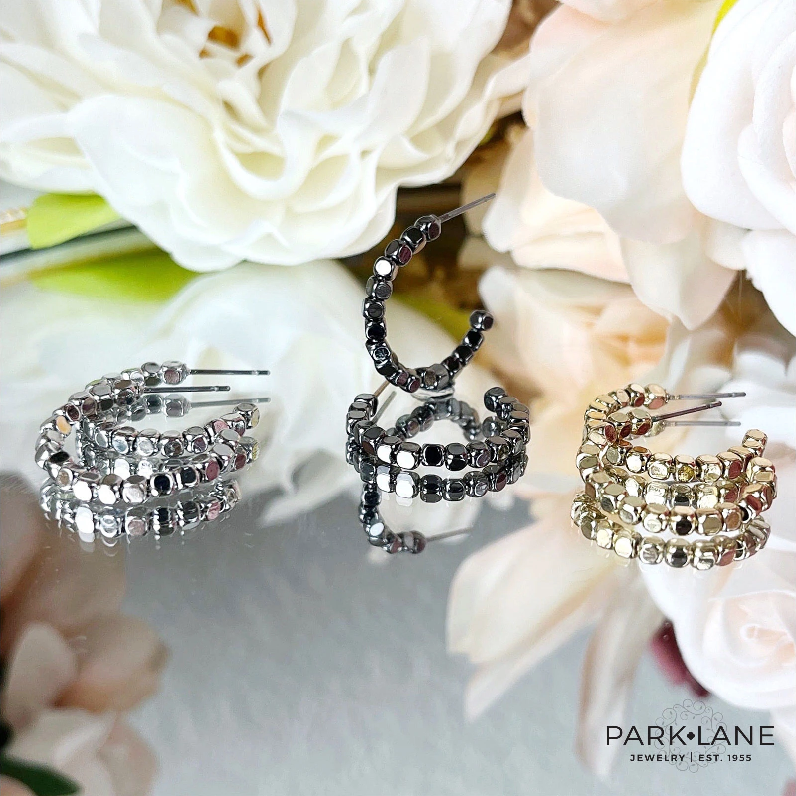 Sparkly Park Lane earrings and jewelry styled on a dark background