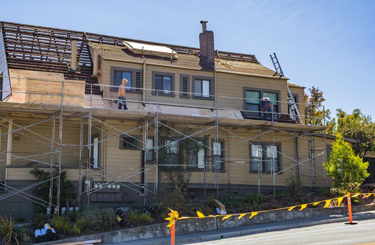 Workers installing shingles on a steep residential roof