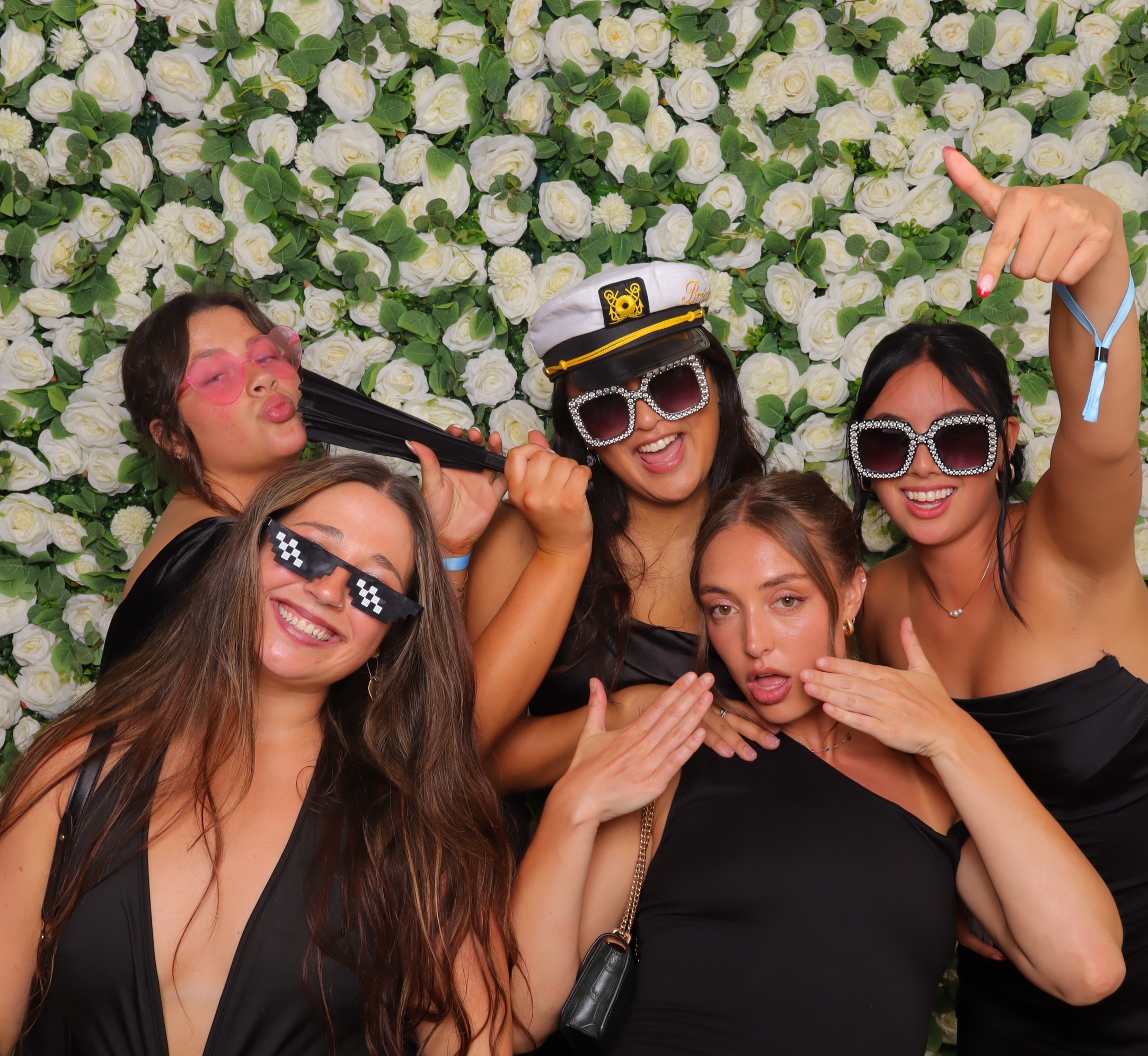 Women with sunglasses and captain hat in front of the flower wall