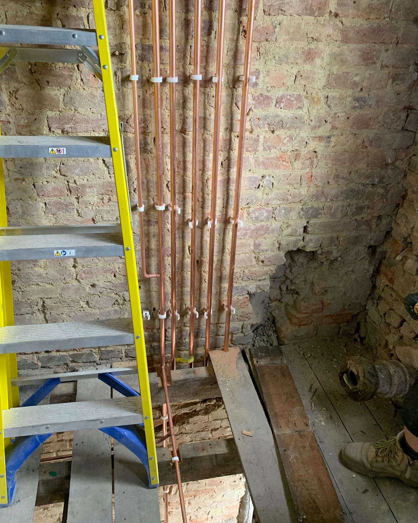 Copper pipework installation against a brick wall