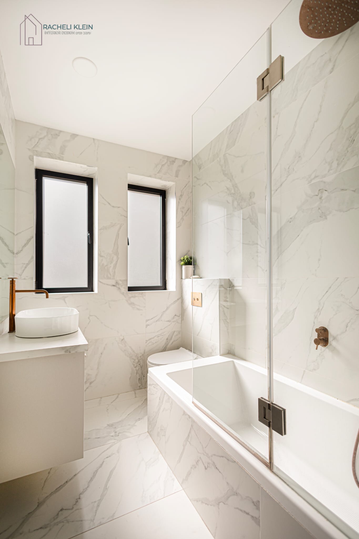 Elegant custom bathroom design in Israel with marble tiles and glass shower enclosure by Racheli Klein