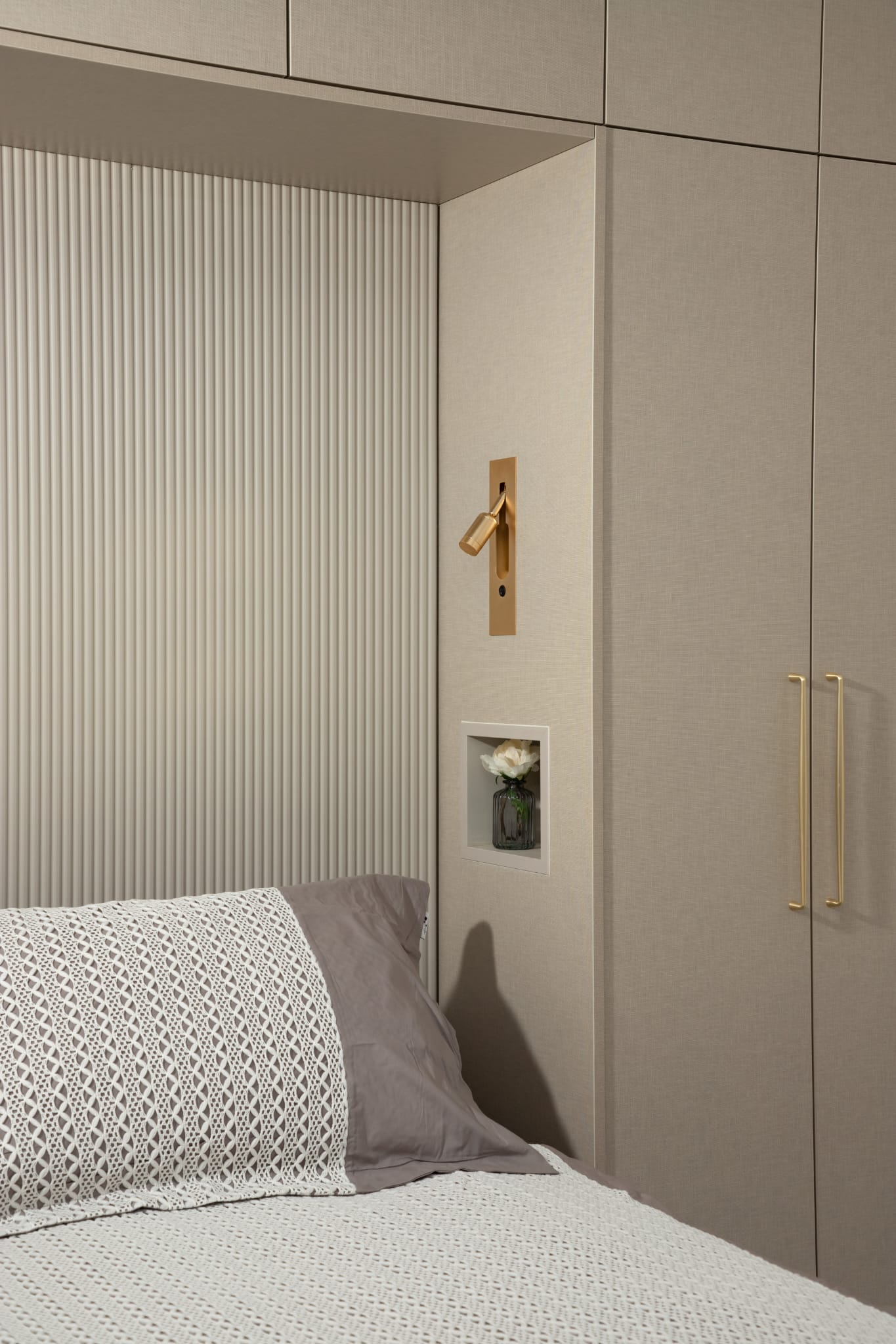 Bedroom detail with textured wall and gold reading light