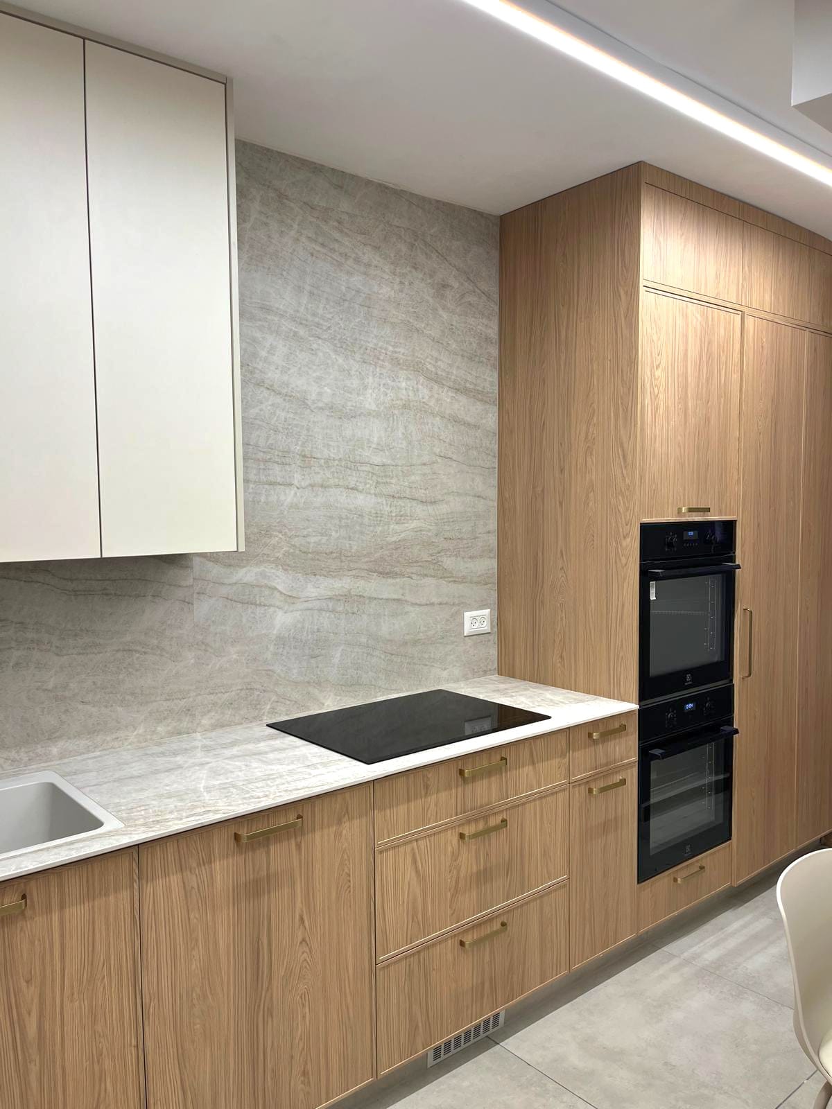 Modern kitchen with wood cabinetry, marble backsplash, and built-in appliances