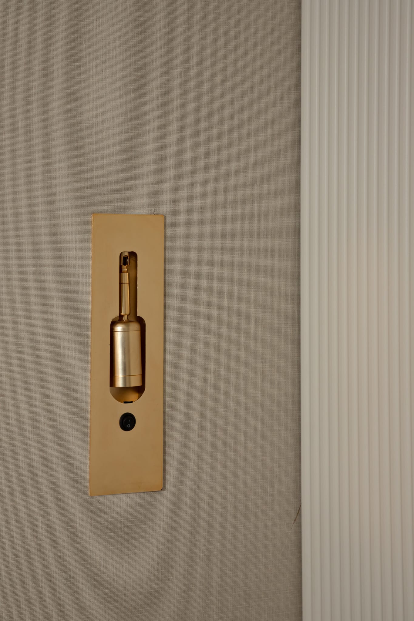 Gold light switch detail on textured wall