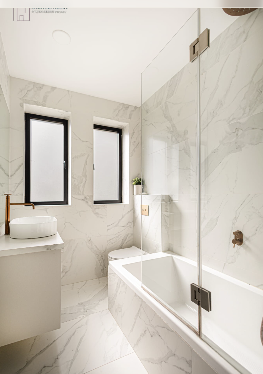 Custom bathroom design in Israel with marble tiles and glass shower enclosure by Racheli Klein