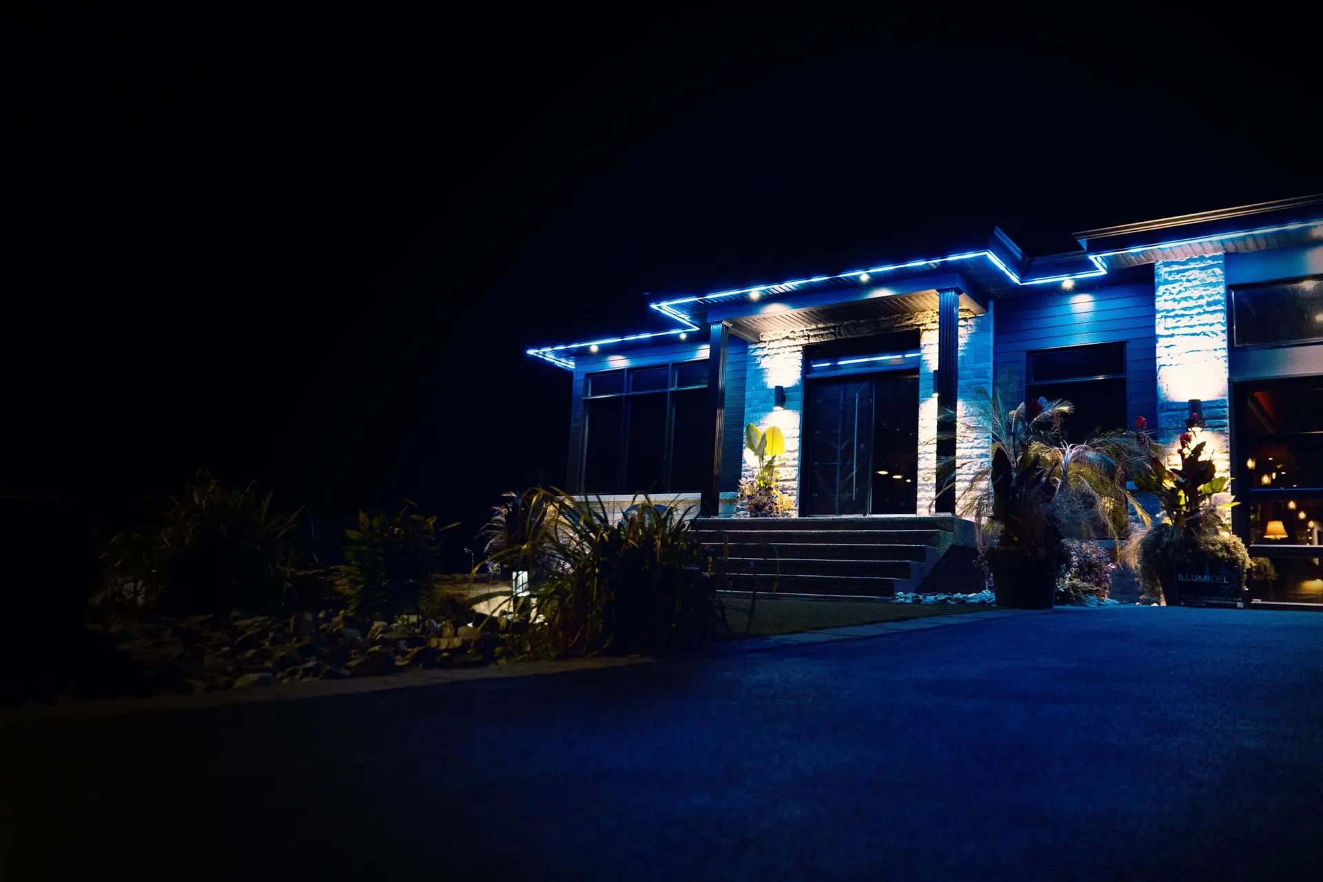 Two-story home illuminated with festive roofline lighting