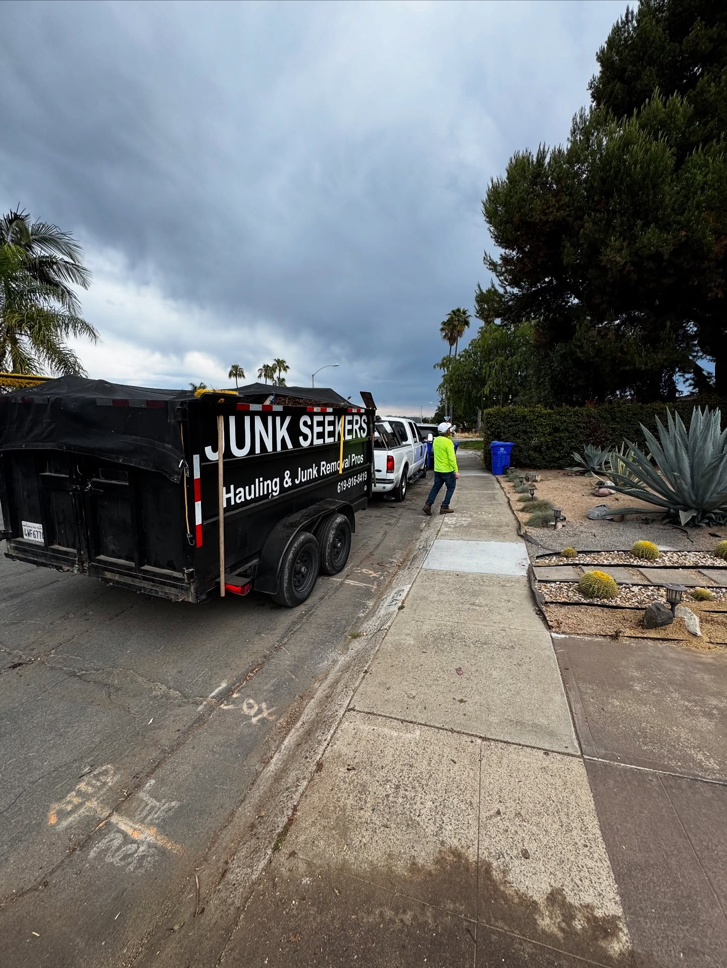 A black construction debris dump trailer parked safely at a residential job site
