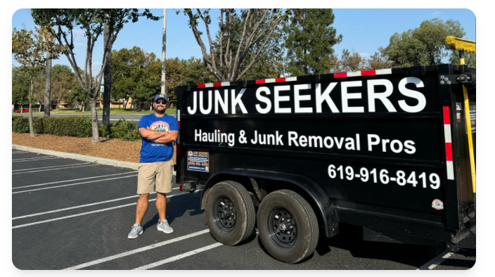 Santiago from Junk Seekers standing proudly next to a branded junk removal trailer