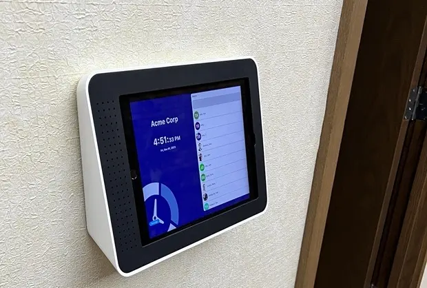 Wall-mounted digital tablet time clock with employee list and clock-in interface connected to Auris payroll