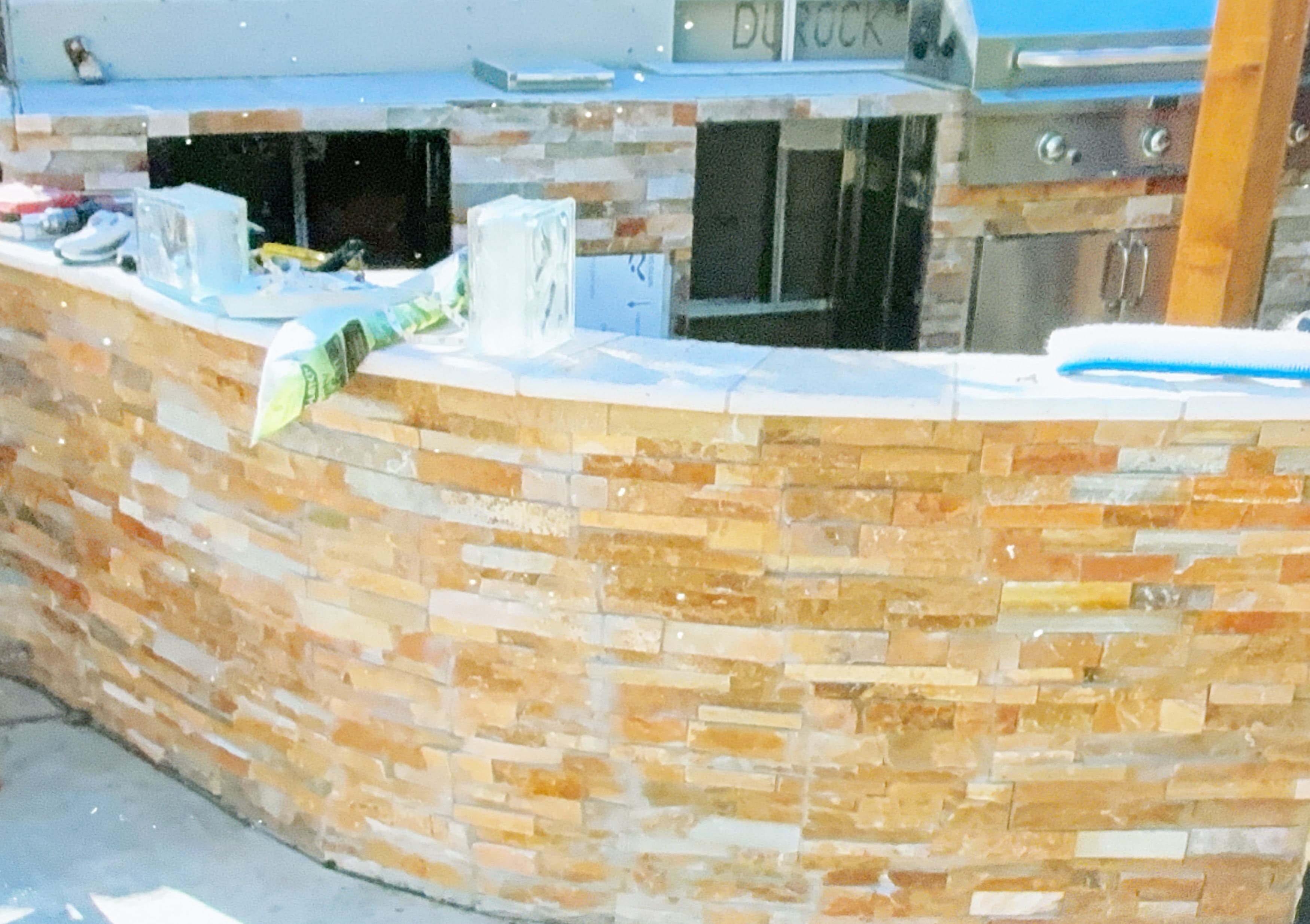 Custom outdoor kitchen island under construction with stone veneer
