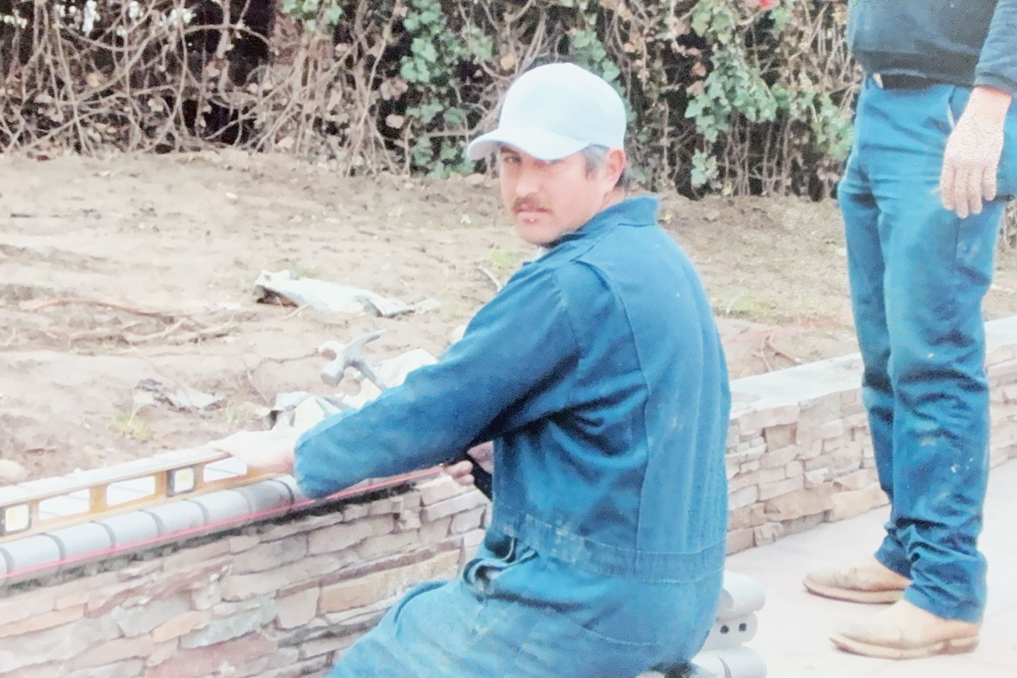 Worker constructing a low stone retaining wall
