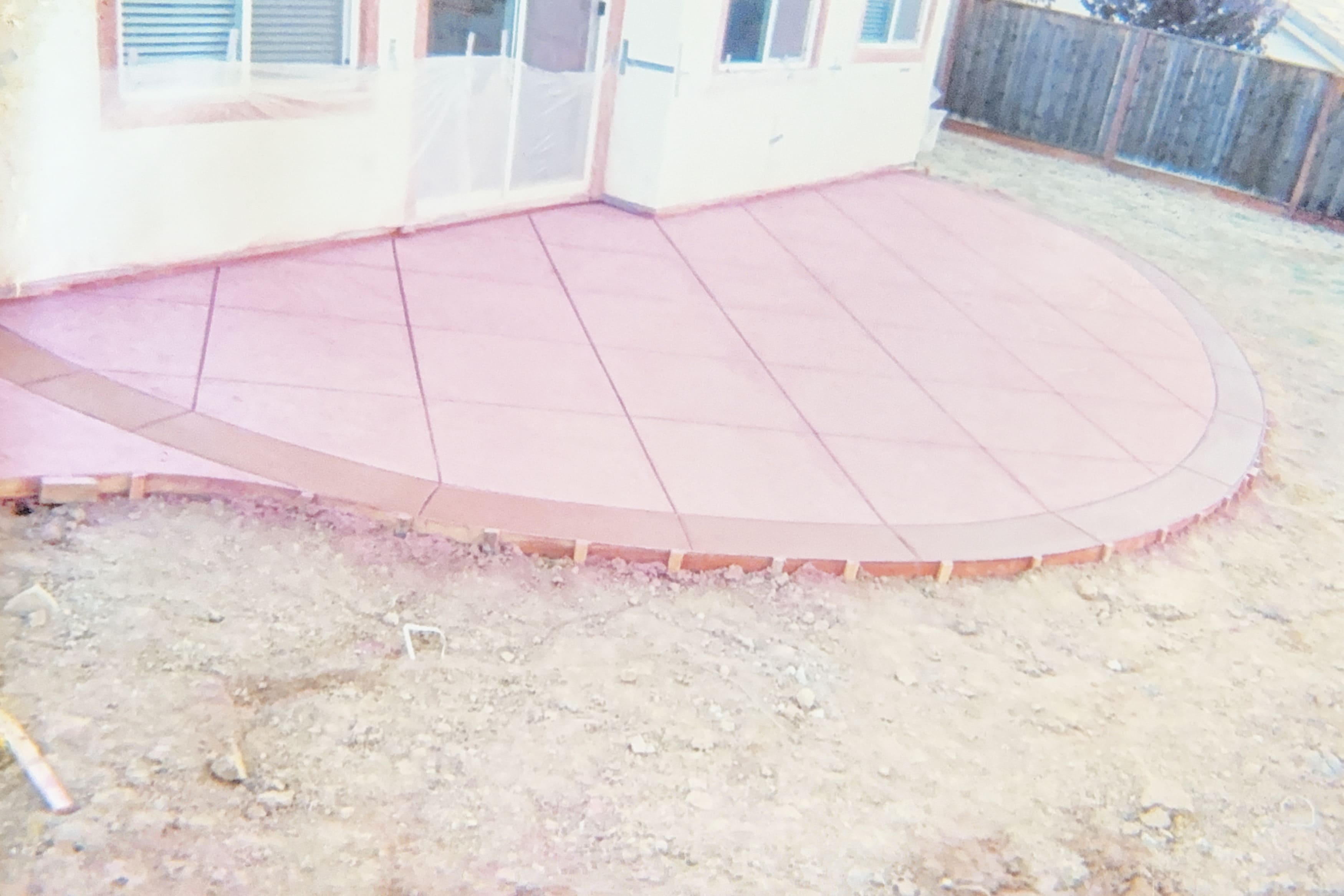 Newly poured concrete patio with a curved edge and diamond scoring pattern