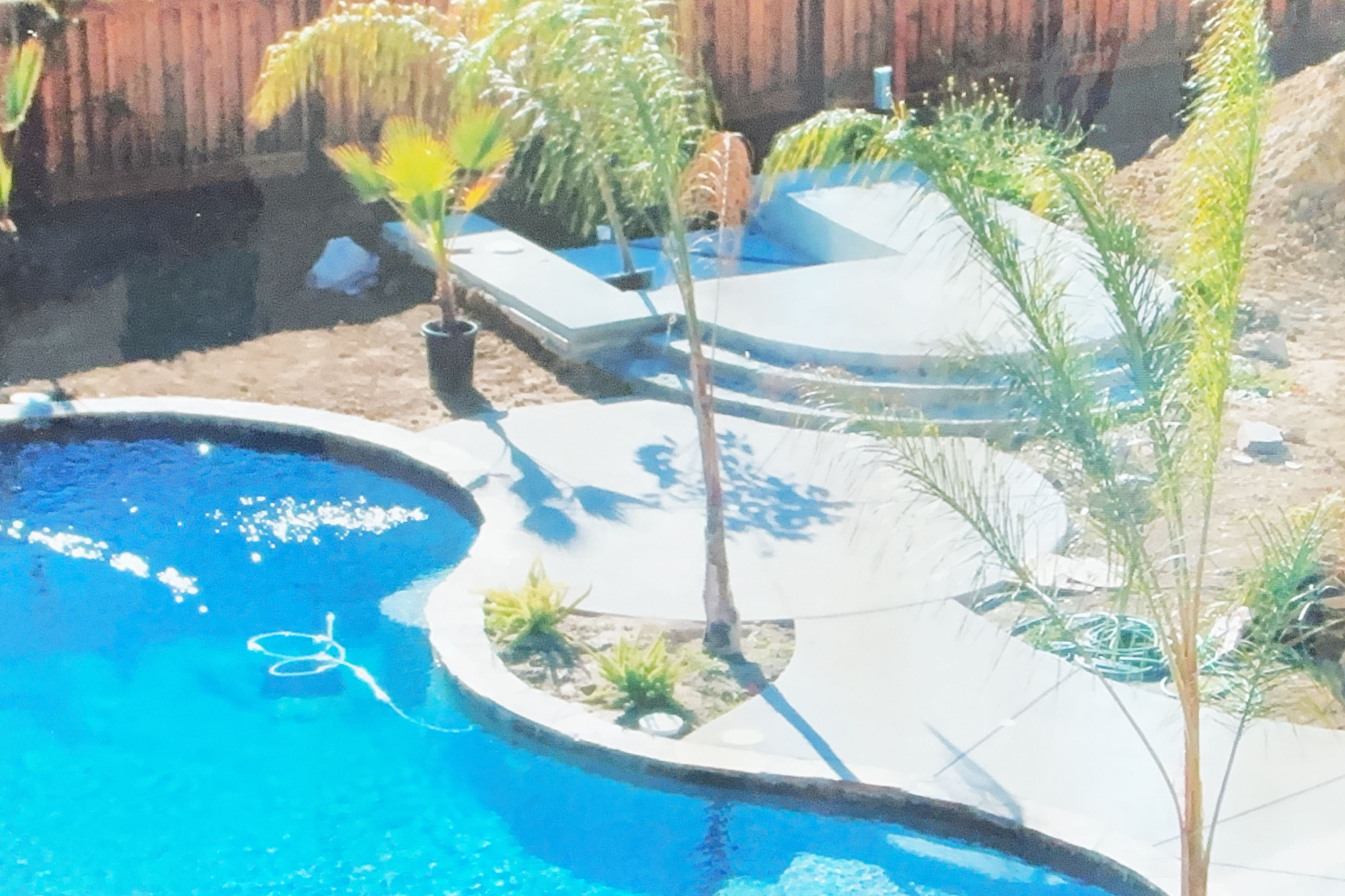 Swimming pool and concrete deck under construction with palm trees